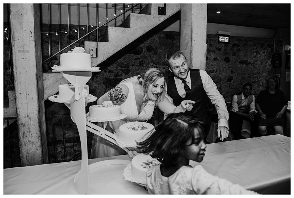 bride pointing to young girl as they cut their wedding cake at their castle koniz wedding reception in bern Switzerland