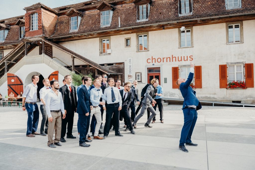 garter in mid air as groom leans back and men try to catch it at Kulturhof Schloss Köniz in bern Switzerland