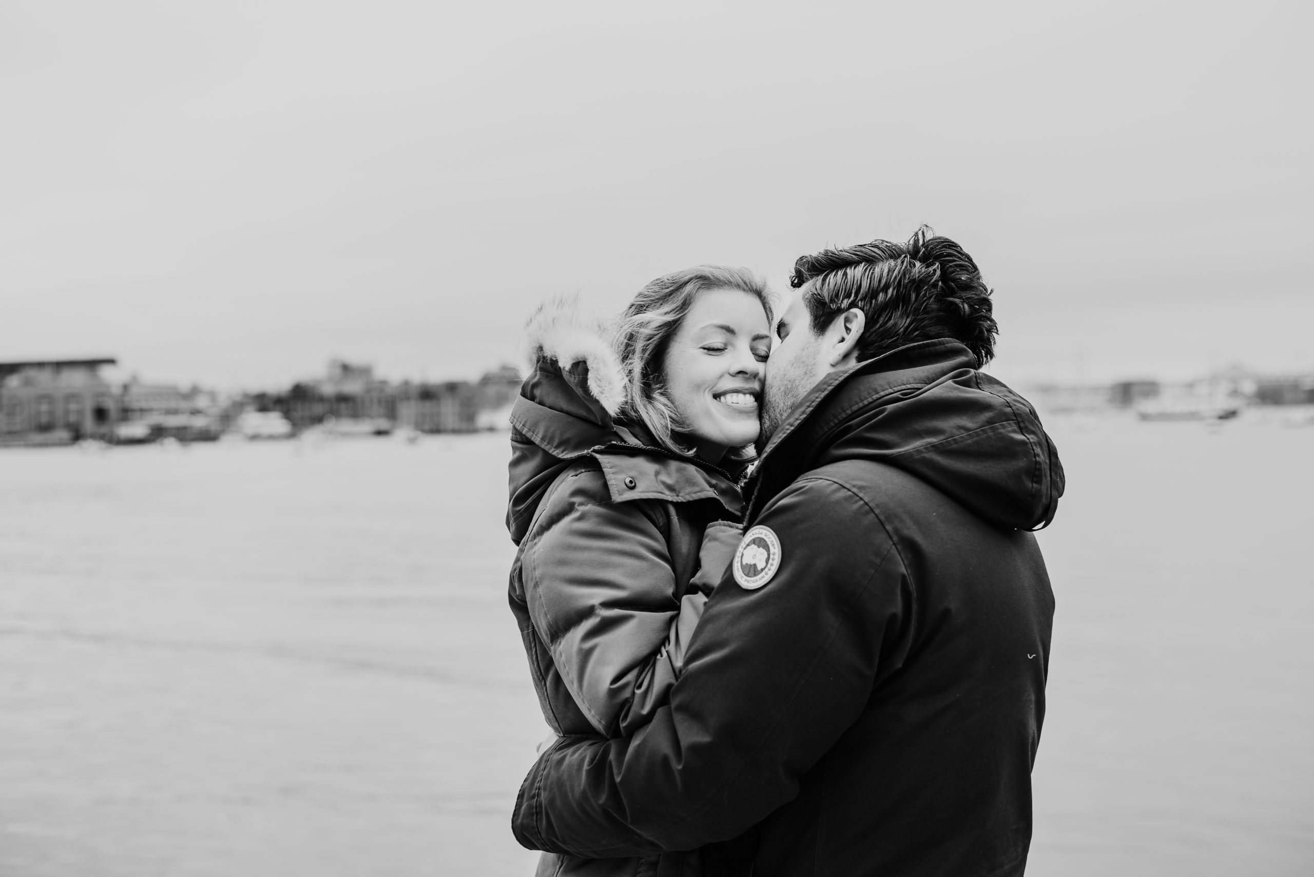 Couple kissing during winter engagement session in the Boston Seaport District at Fan Pier Park