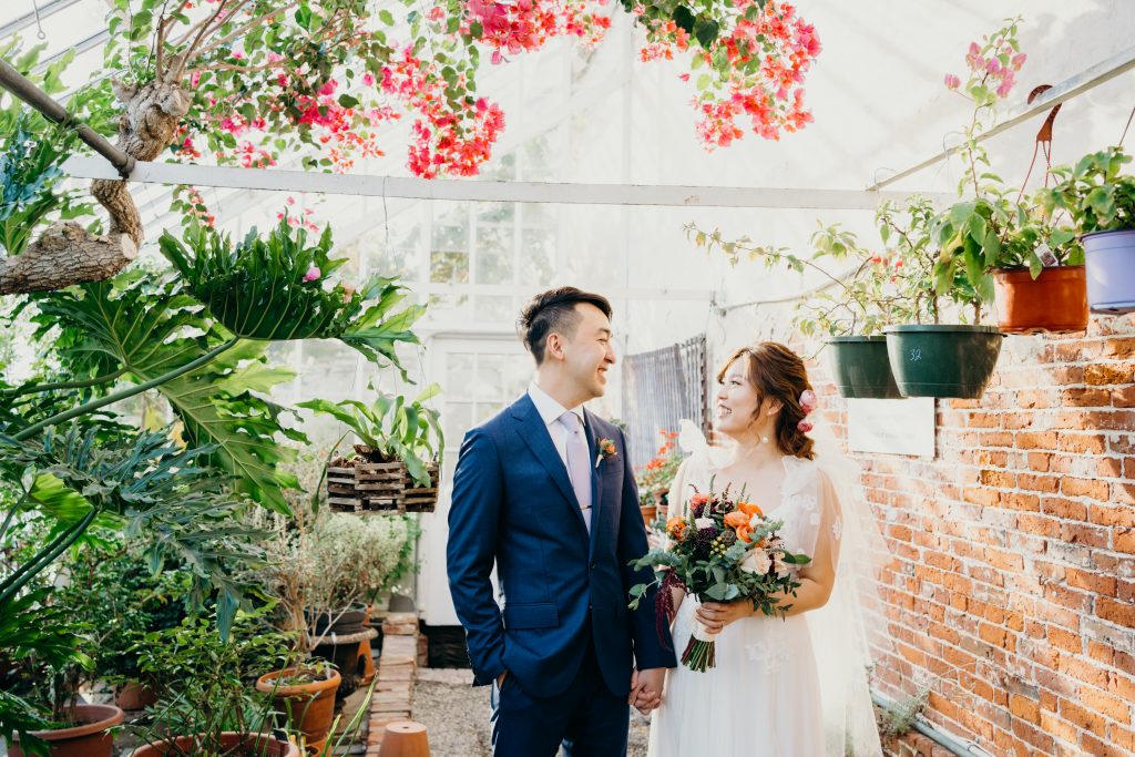 bride and groom walking in the greenhouse at the Lyman Estate during their MA wedding