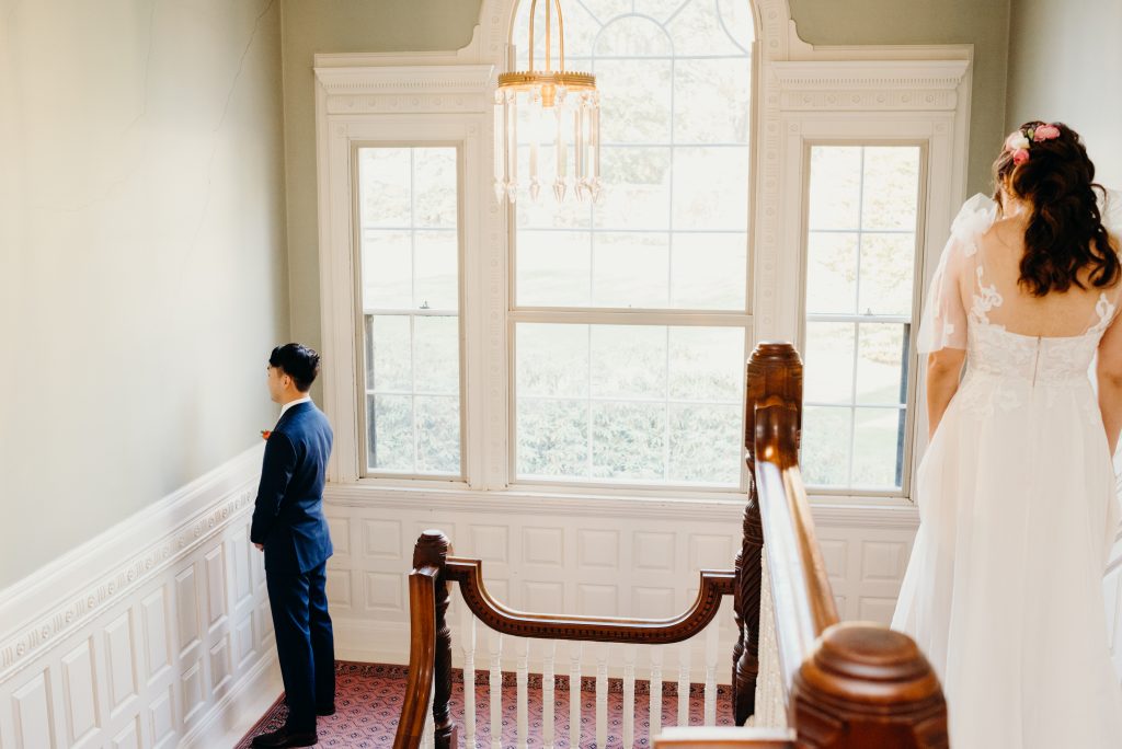 bride walking to groom for their first look at the Lyman Estate staircase