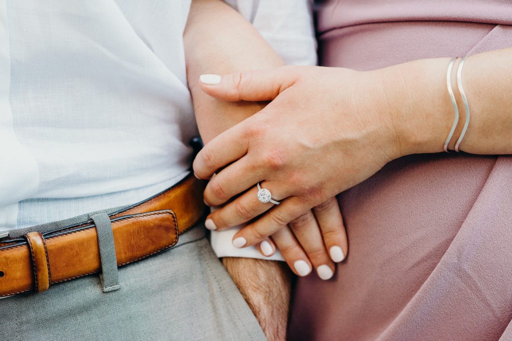 closeup photo of engagement ring while a couple are arm and arm after their boston proposal