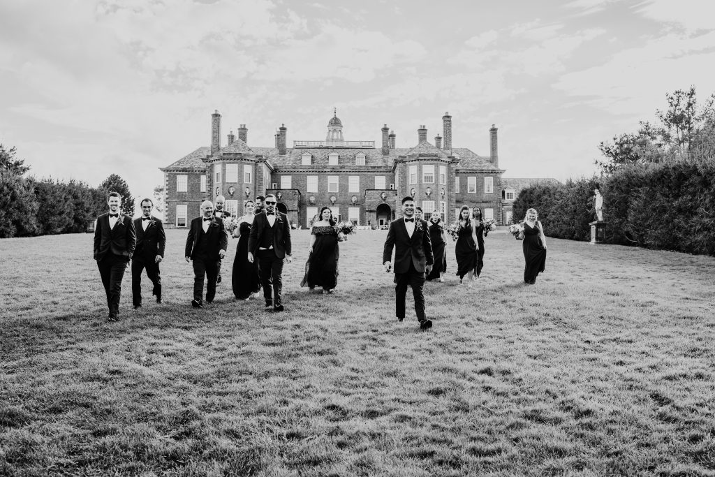 black and white photo of wedding party walking down the grand Allee at the crane estate wedding venue in Ipswich massachusetts