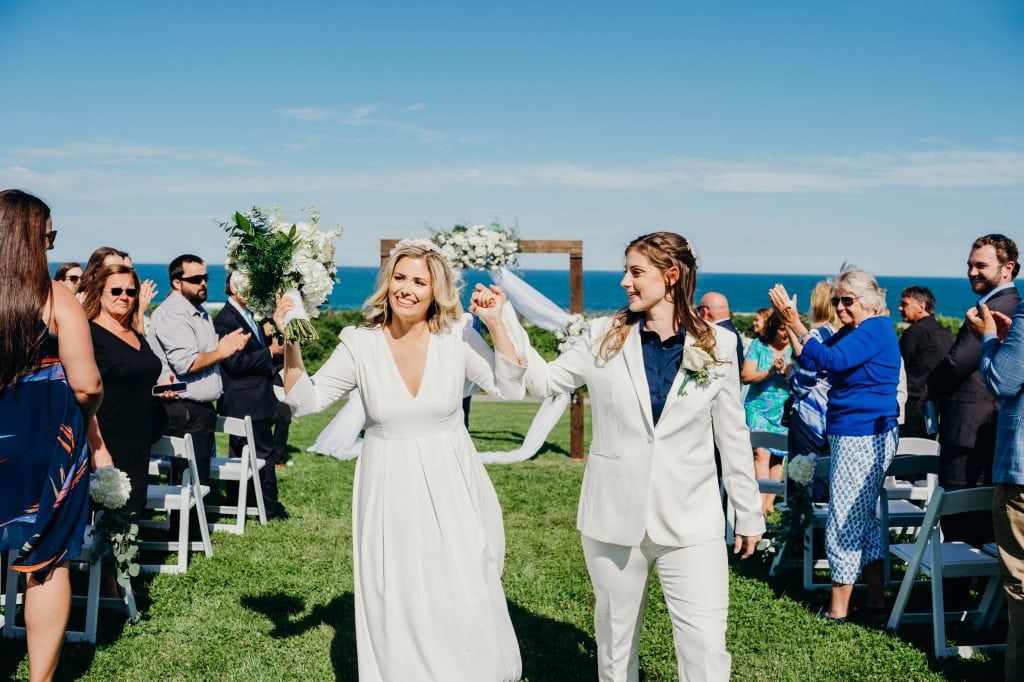 just married brides walking hand in hand back down the aisle during their Cape Cod wedding at the Nauset Beach Inn