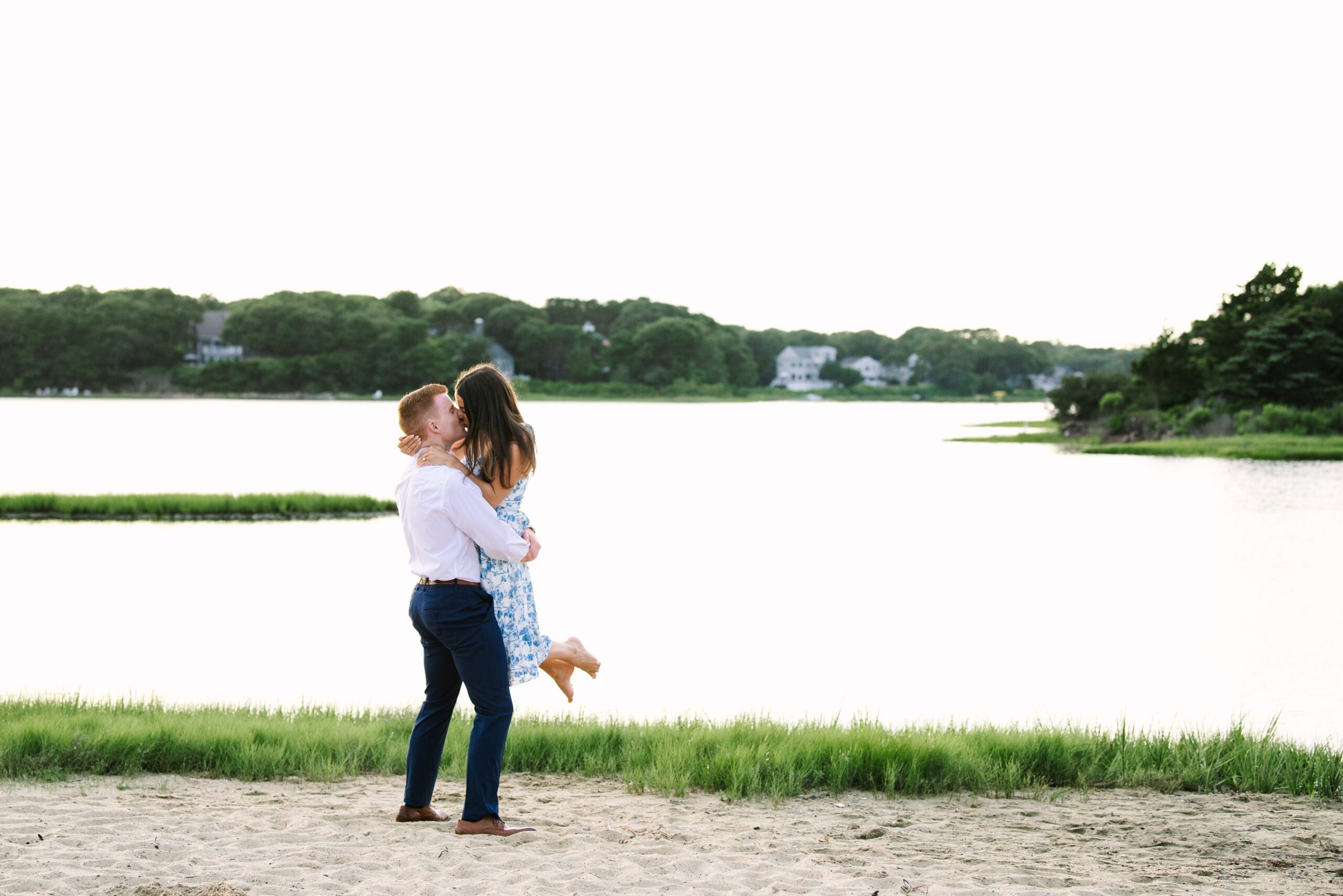 guy lifting up fiance and kissing her during their cape cod surprise proposal session in massachusetts