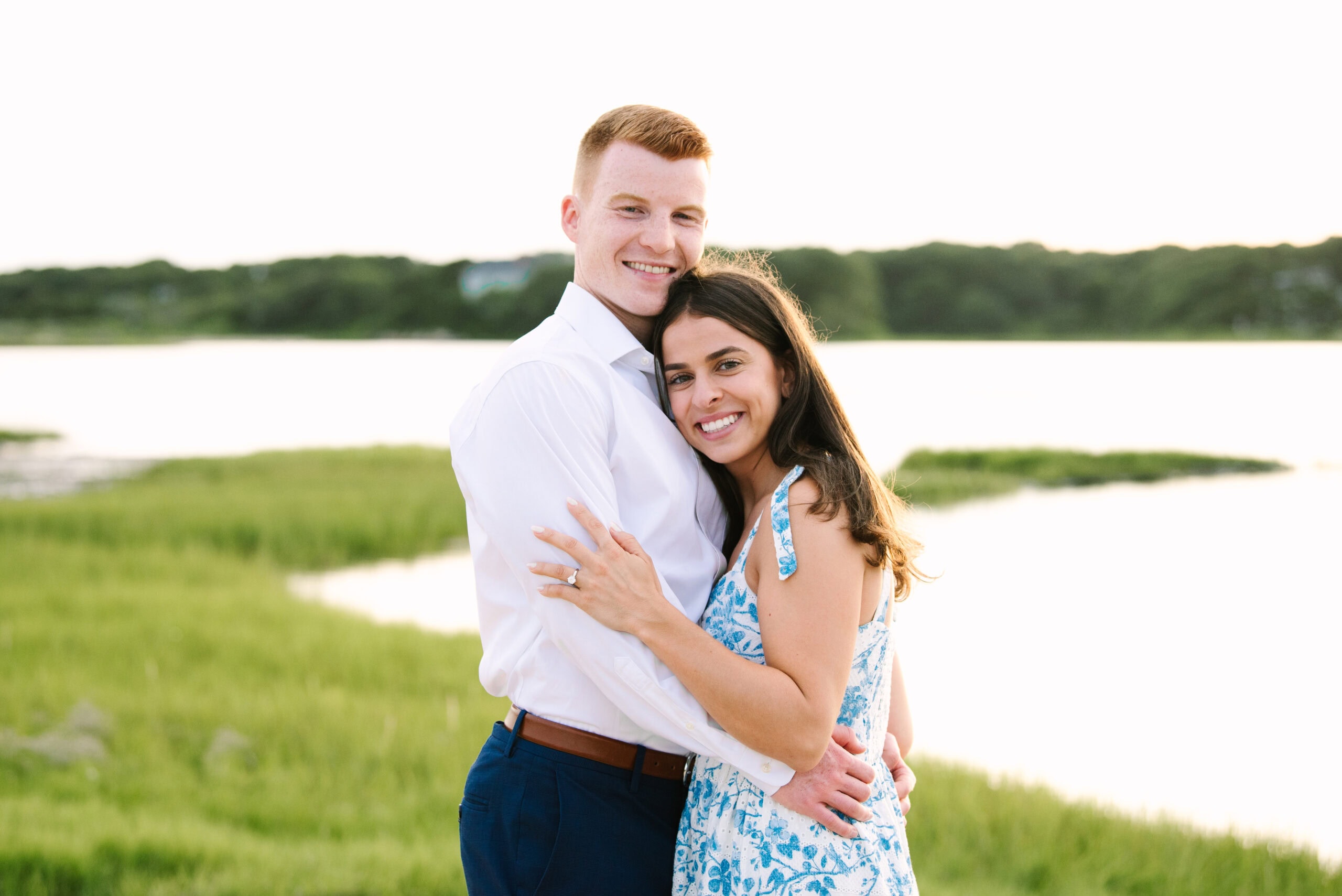 just engaged couple smiling at the camera with arms around each other during their falmouth cape cod engagement session