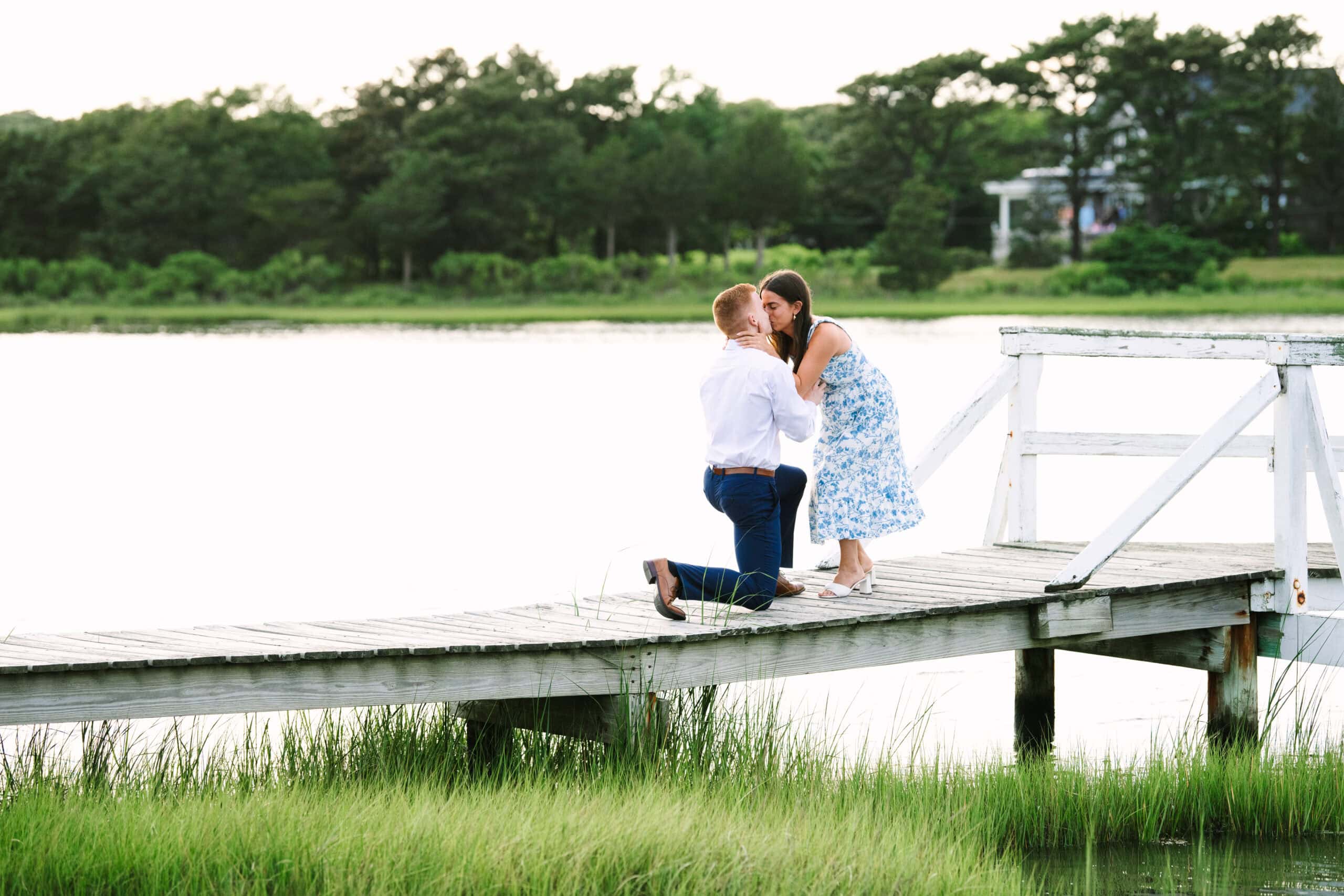 girlfriend kissing guy on his knee proposing during a cape cod surprise proposal