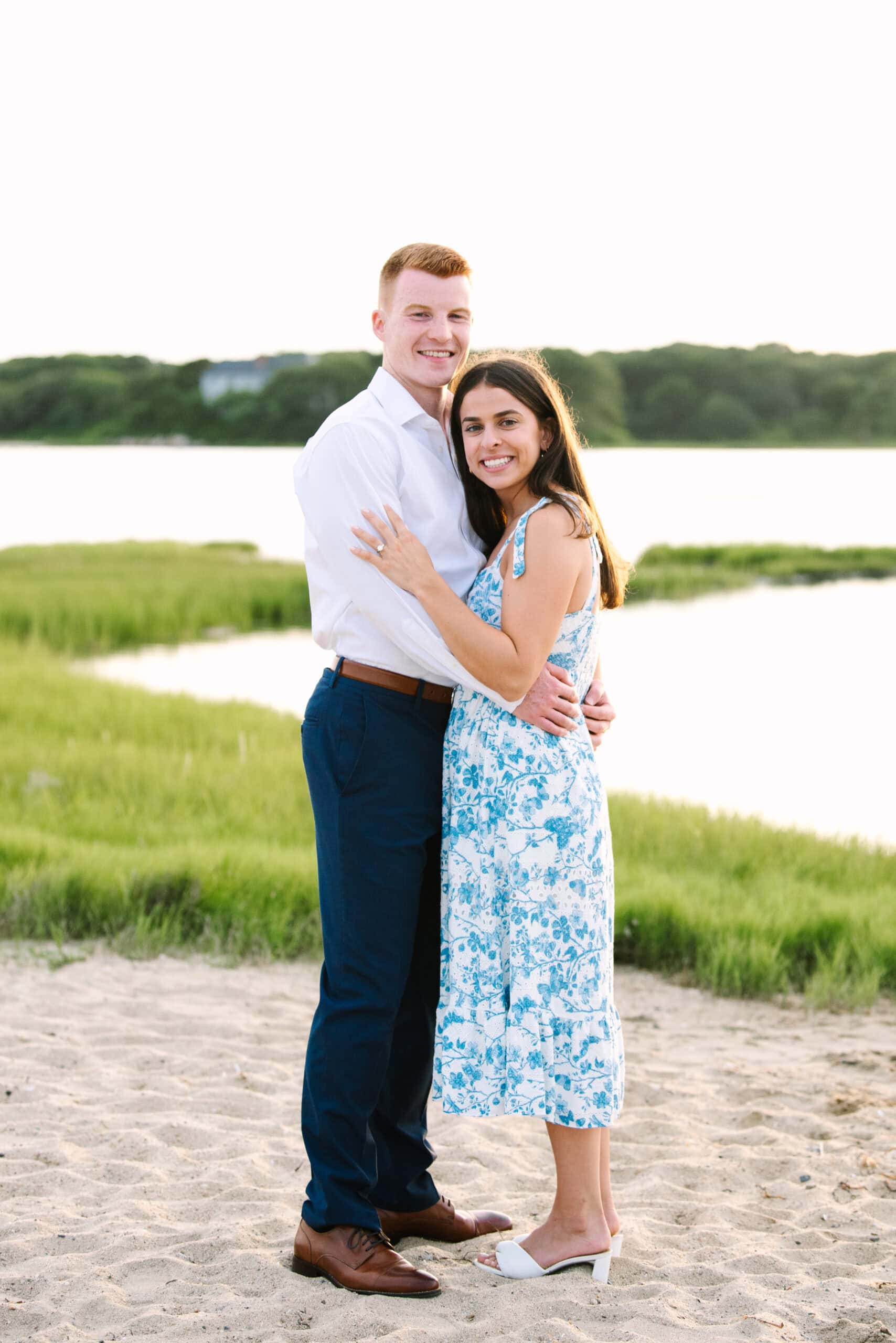 just engaged couple smiling at the camera with arms around each other during their falmouth cape cod engagement session