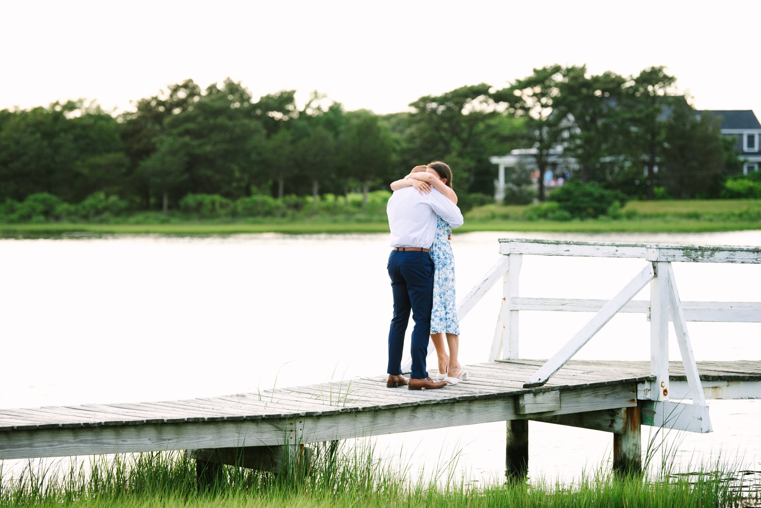 just engaged couple hugging on a white bridge during a falmouth proposal in massachusetts