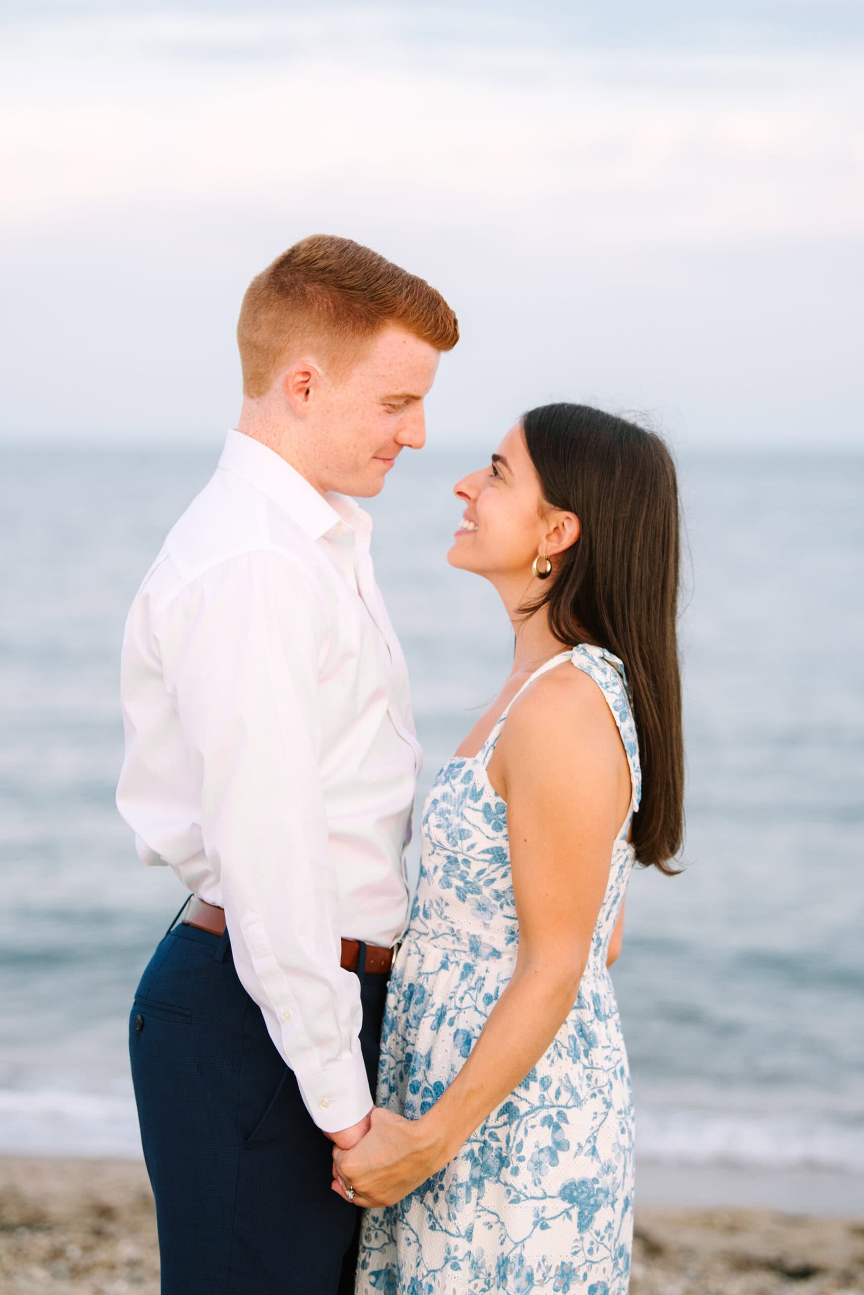 just engaged couple smiling at each other on menahaunt beach during their falmouth cape cod surprise proposal session