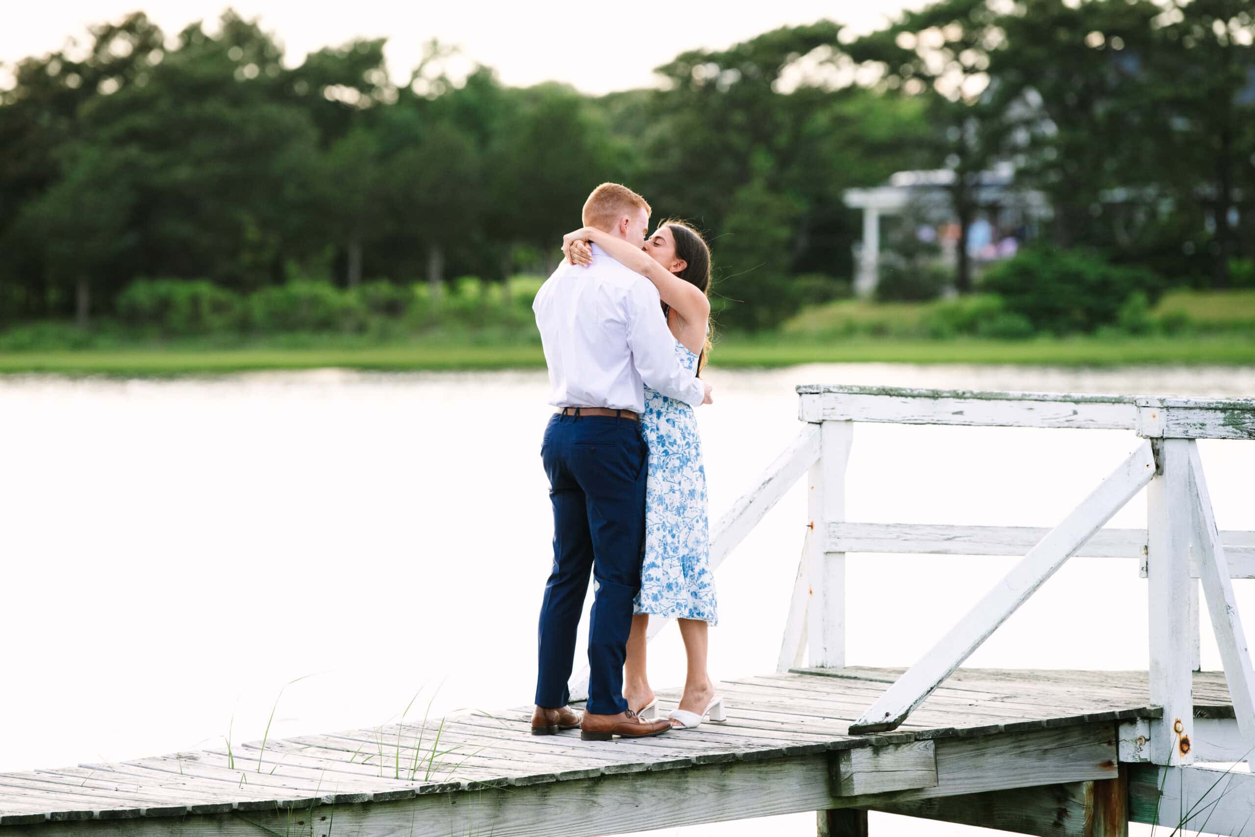 just engaged couple kissing on a white bridge during a falmouth proposal in massachusetts