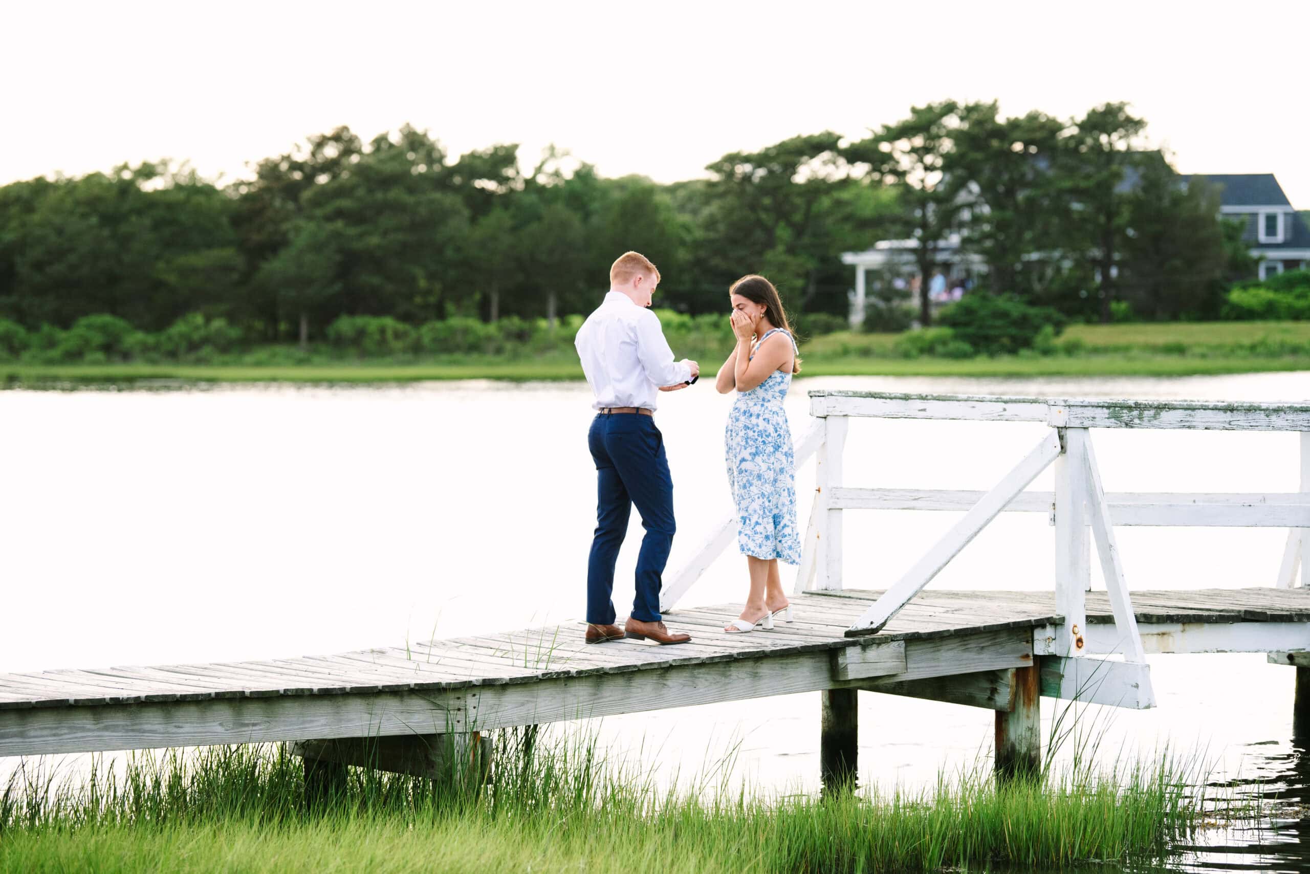 girlfriend hands on face surprised as boyfriend shows the ring during a falmouth proposal in massachusetts