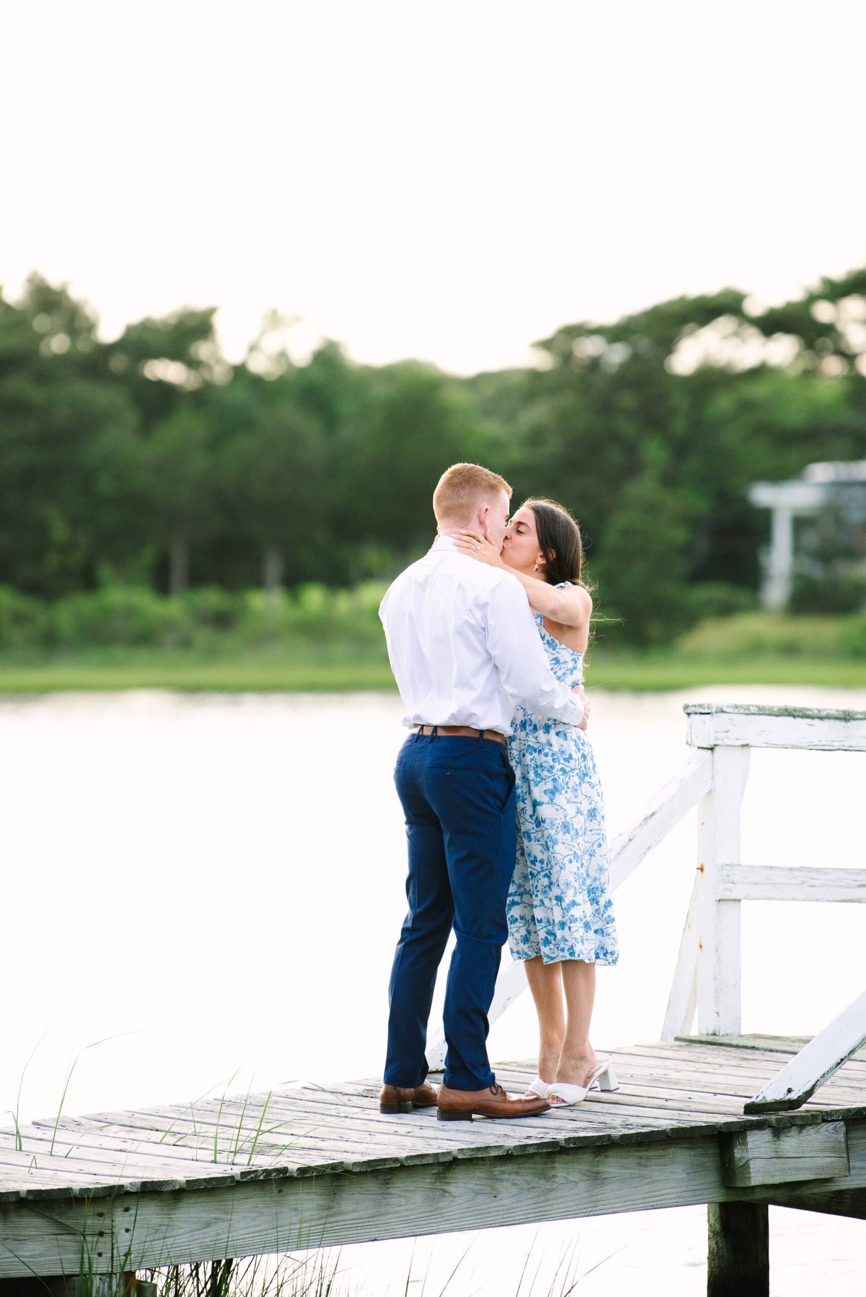 just engaged couple kissing on a white bridge during a falmouth proposal in massachusetts