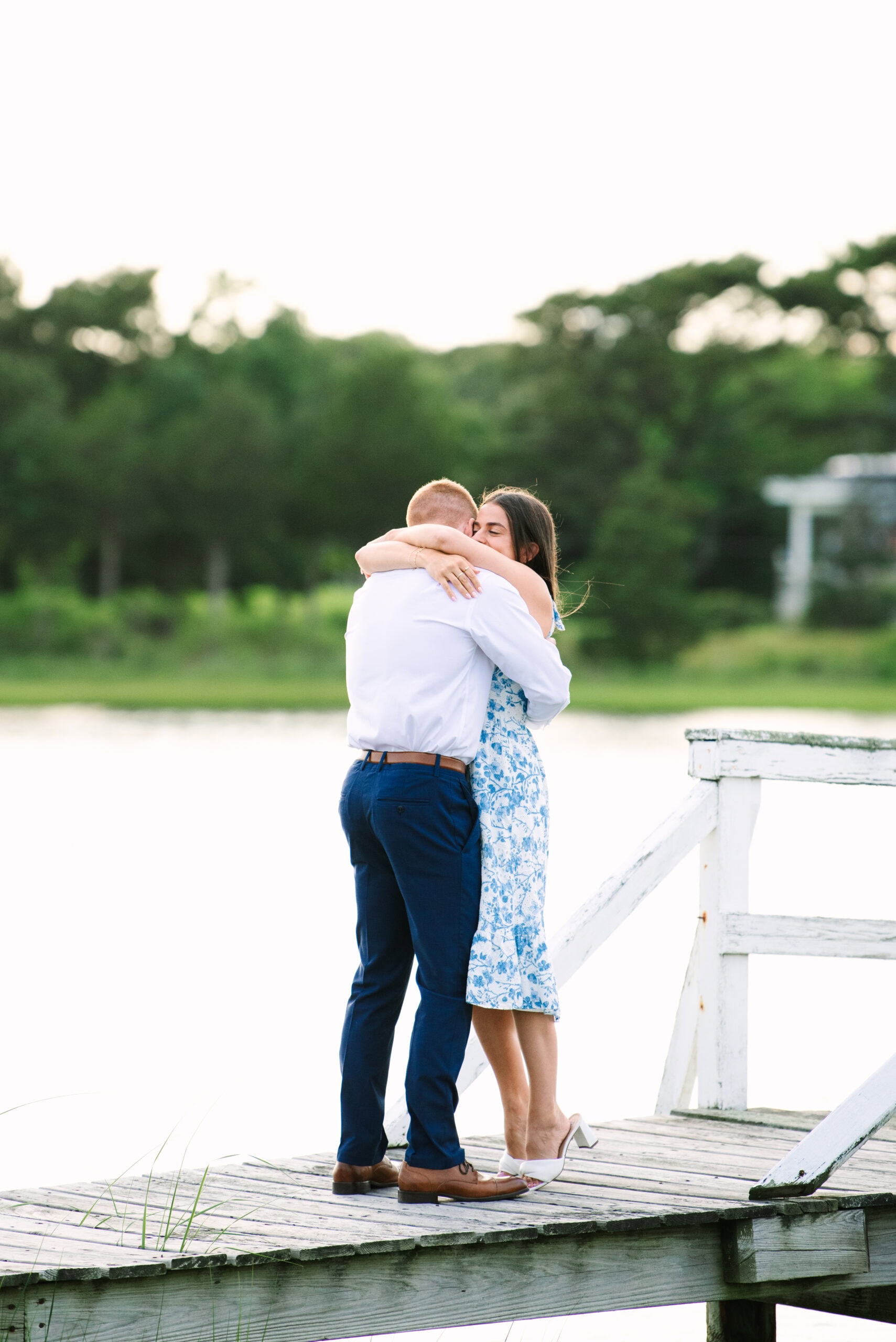 just engaged couple hugging on a white bridge during a falmouth proposal in massachusetts