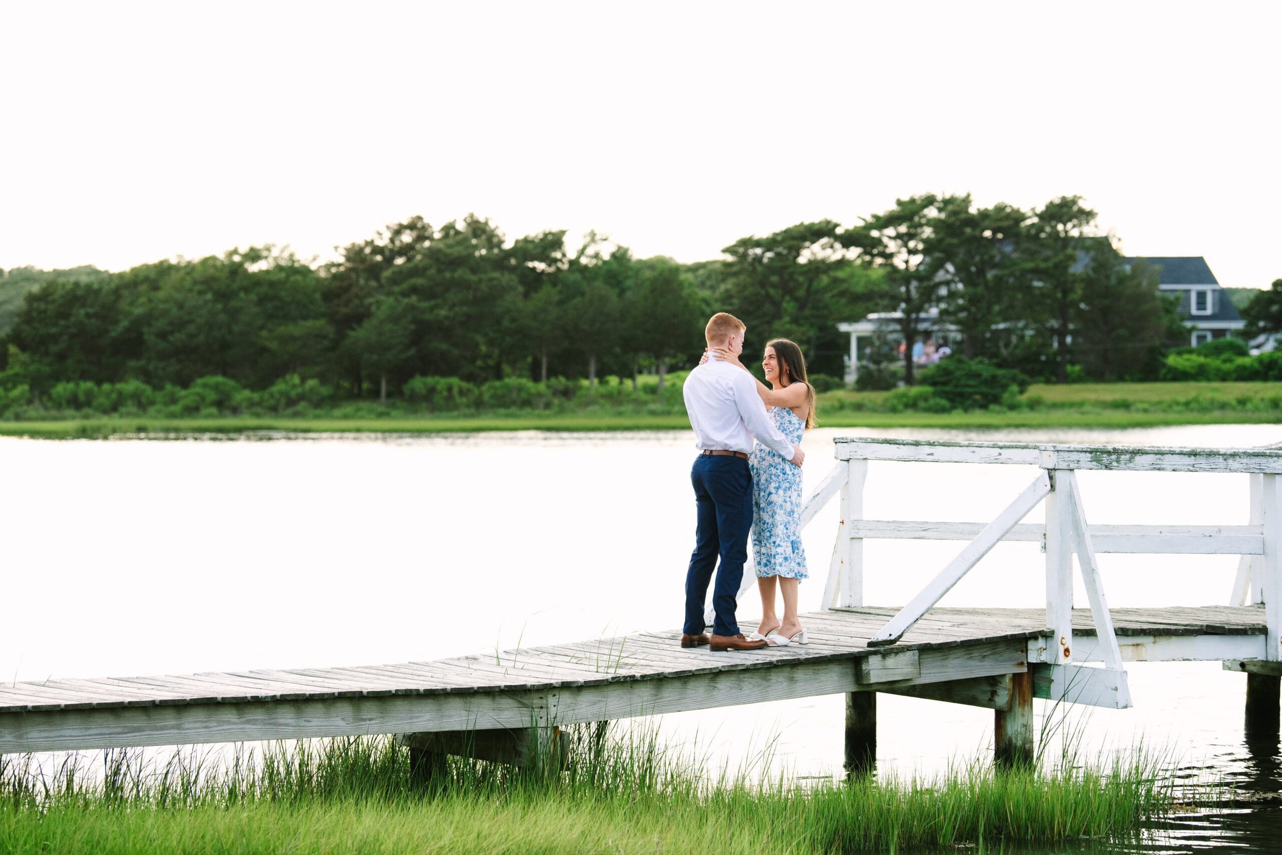 just engaged couple with arms around each other on a white bridge during a falmouth proposal in massachusetts