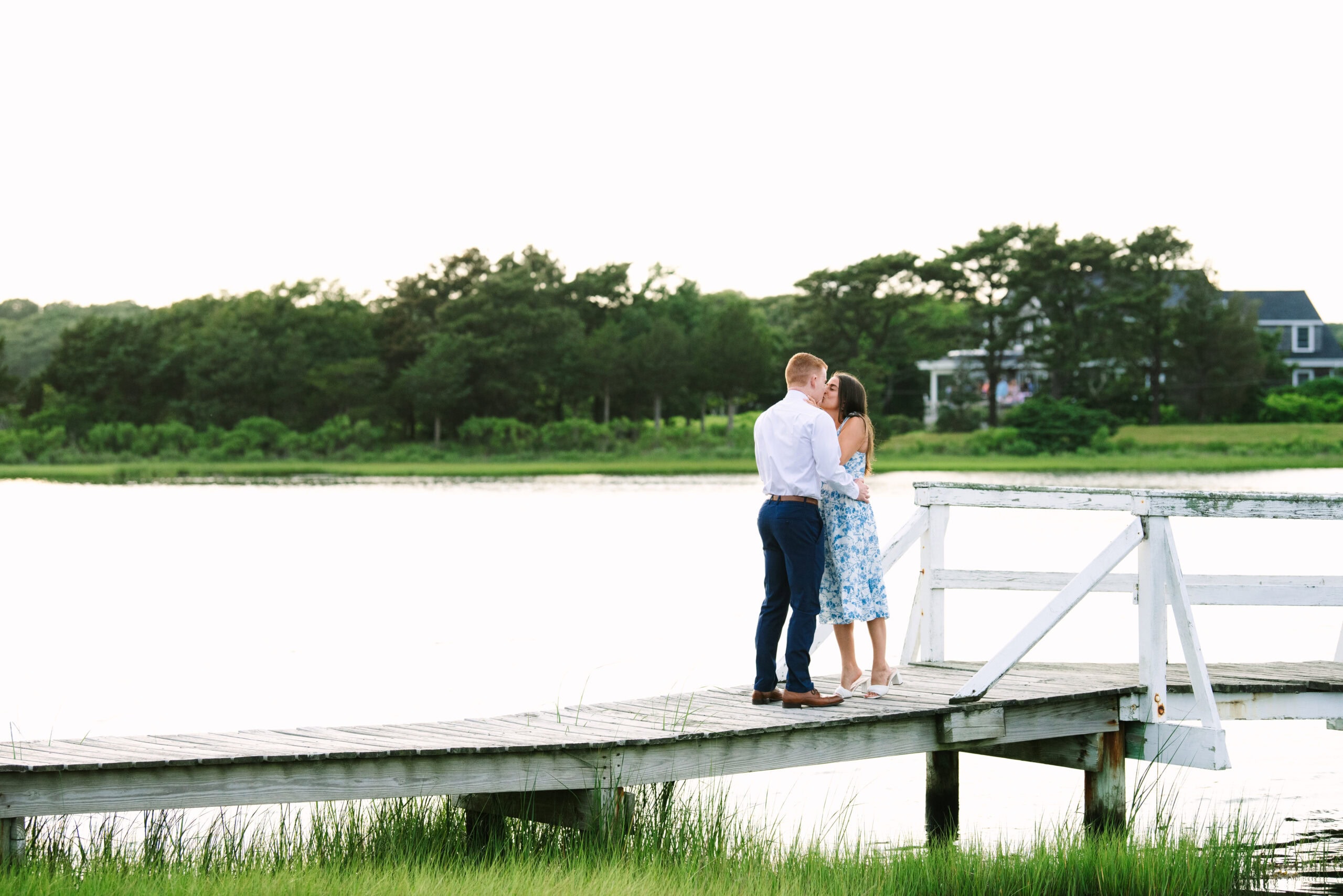 just engaged couple kissing on a white bridge during a falmouth proposal in massachusetts