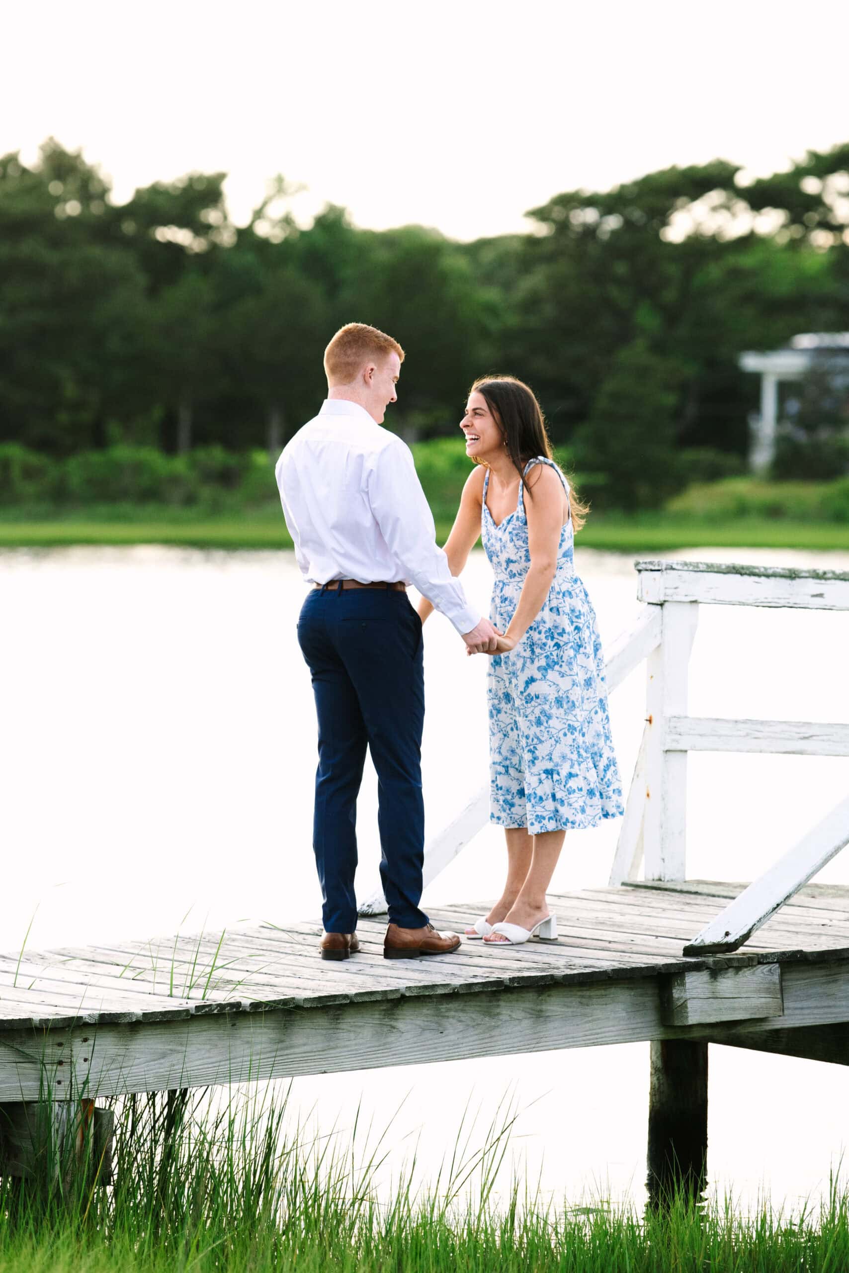 couple holding hands smiling on a bridge after just getting engaged in falmouth massachusetts