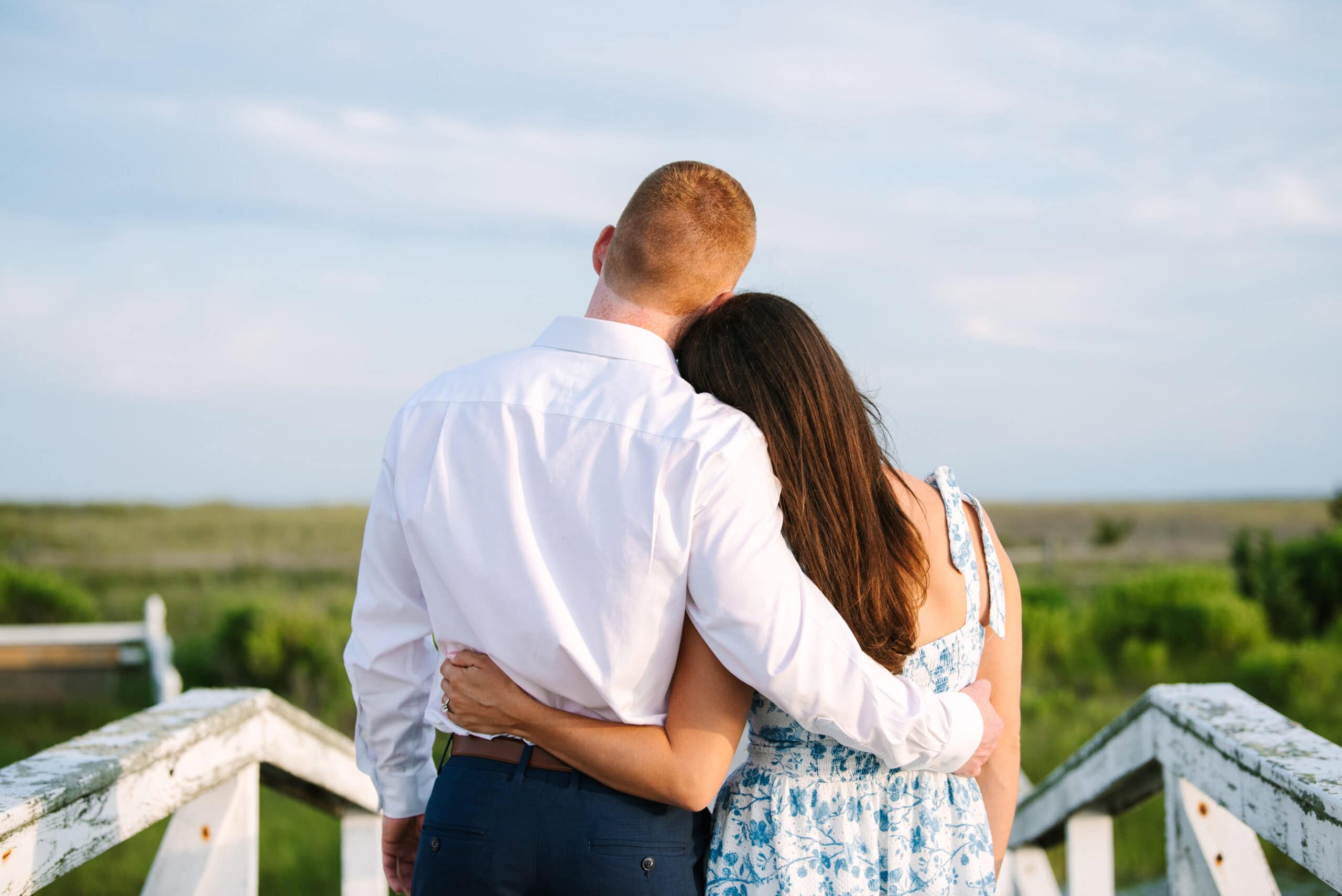 just engaged couple gazing at the view with backs to the camera during a cape cod surprise proposal in massachusetts