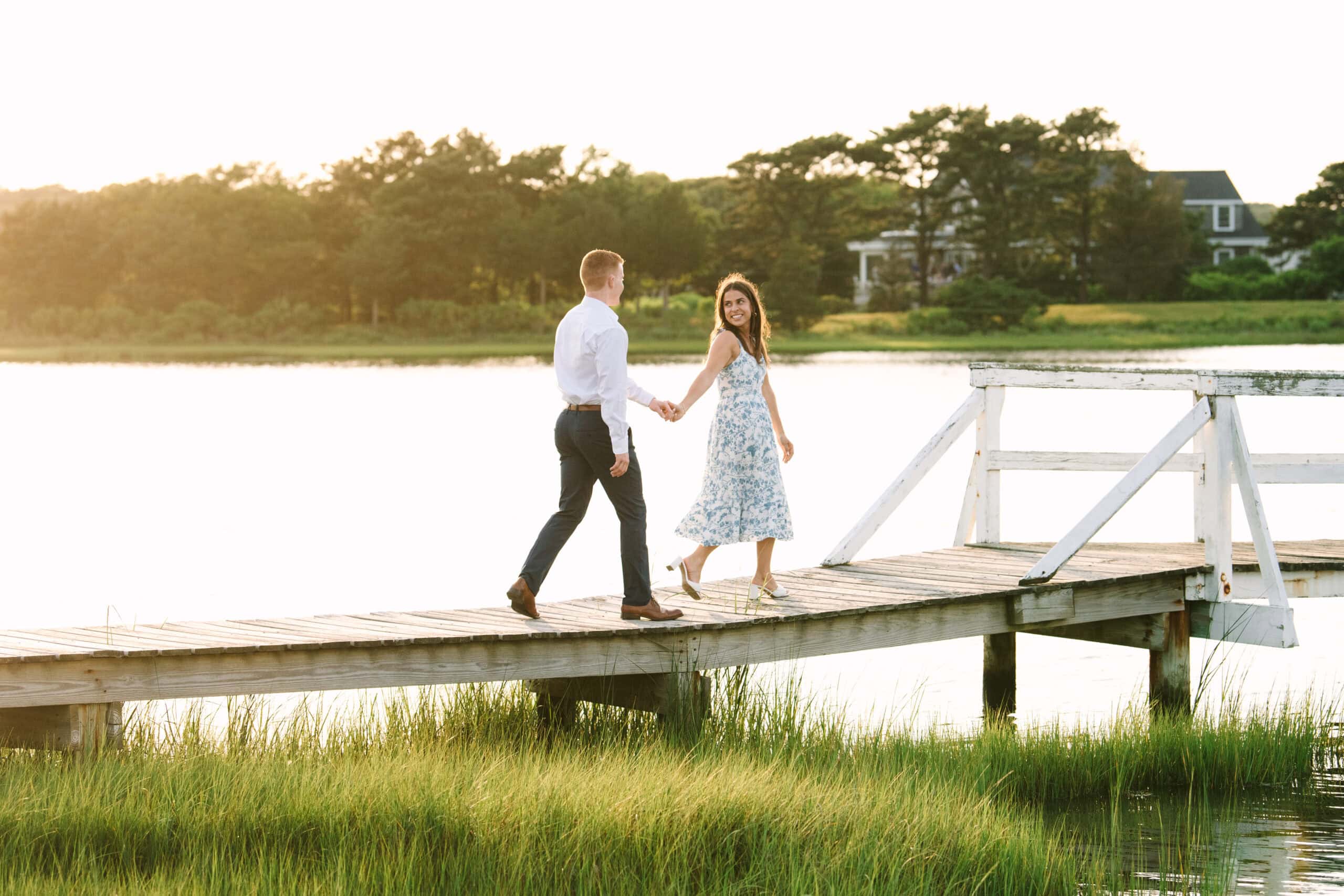 just engaged couple holding hands walking on a bridge during their falmouth cape cod engagement session