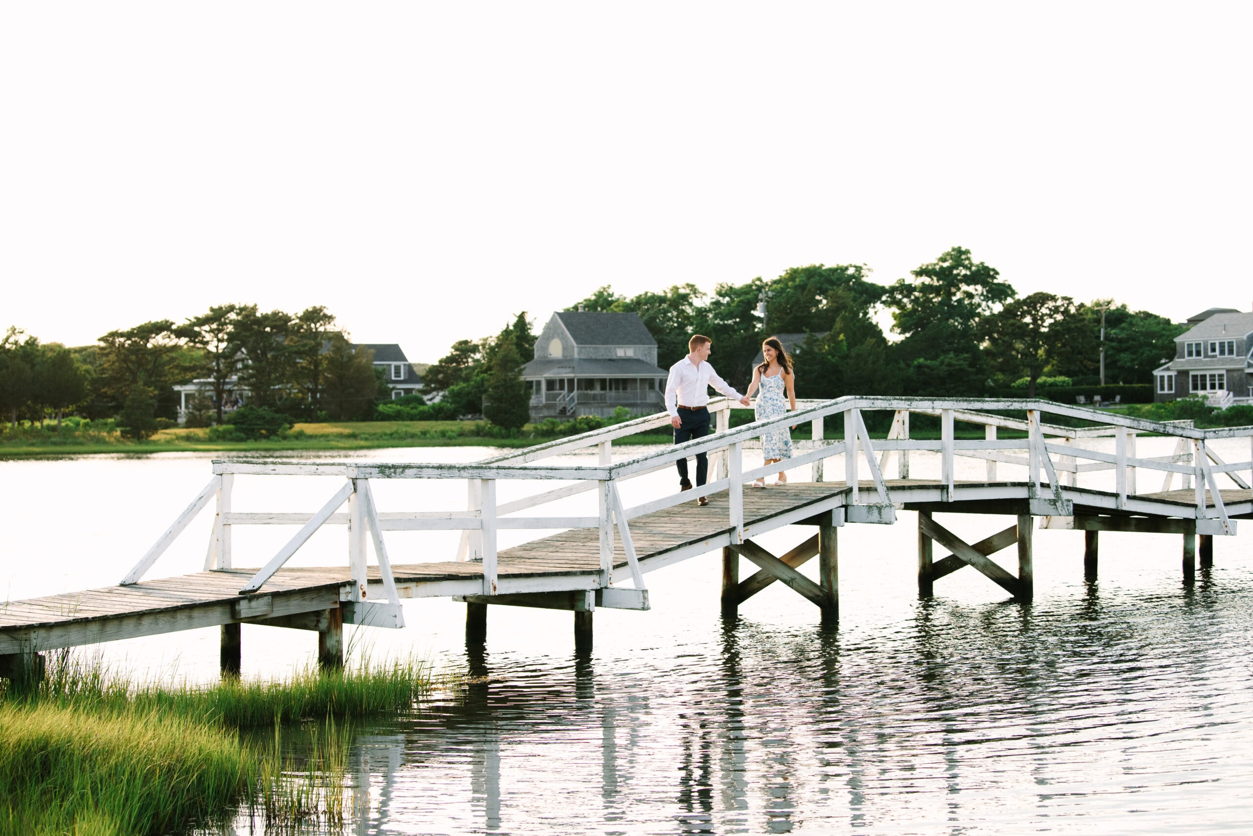 just engaged couple holding hands walking on a bridge during their falmouth cape cod engagement session