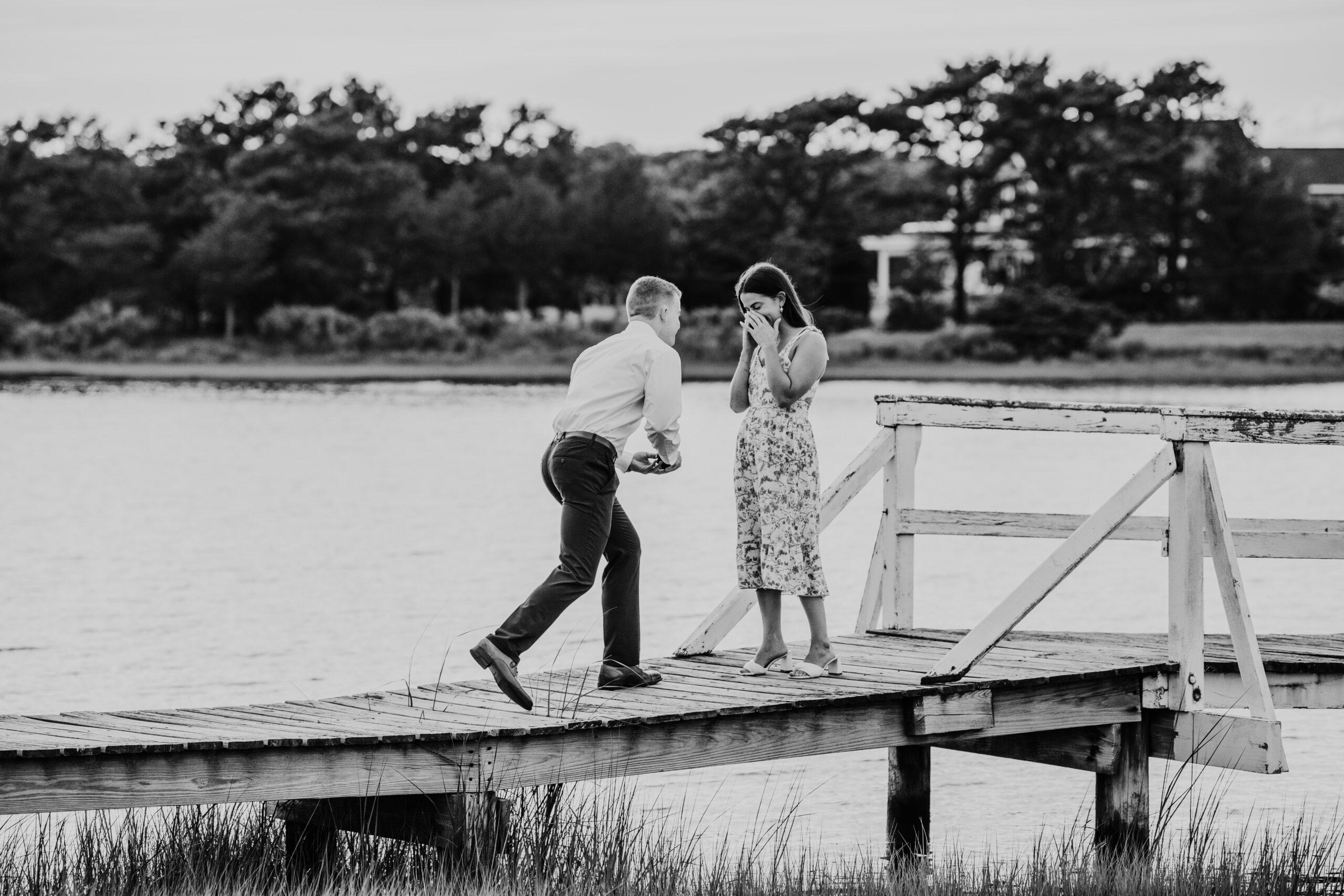 black and white photo of guy proposing to his girlfriend on a bridge in falmouth massachusetts