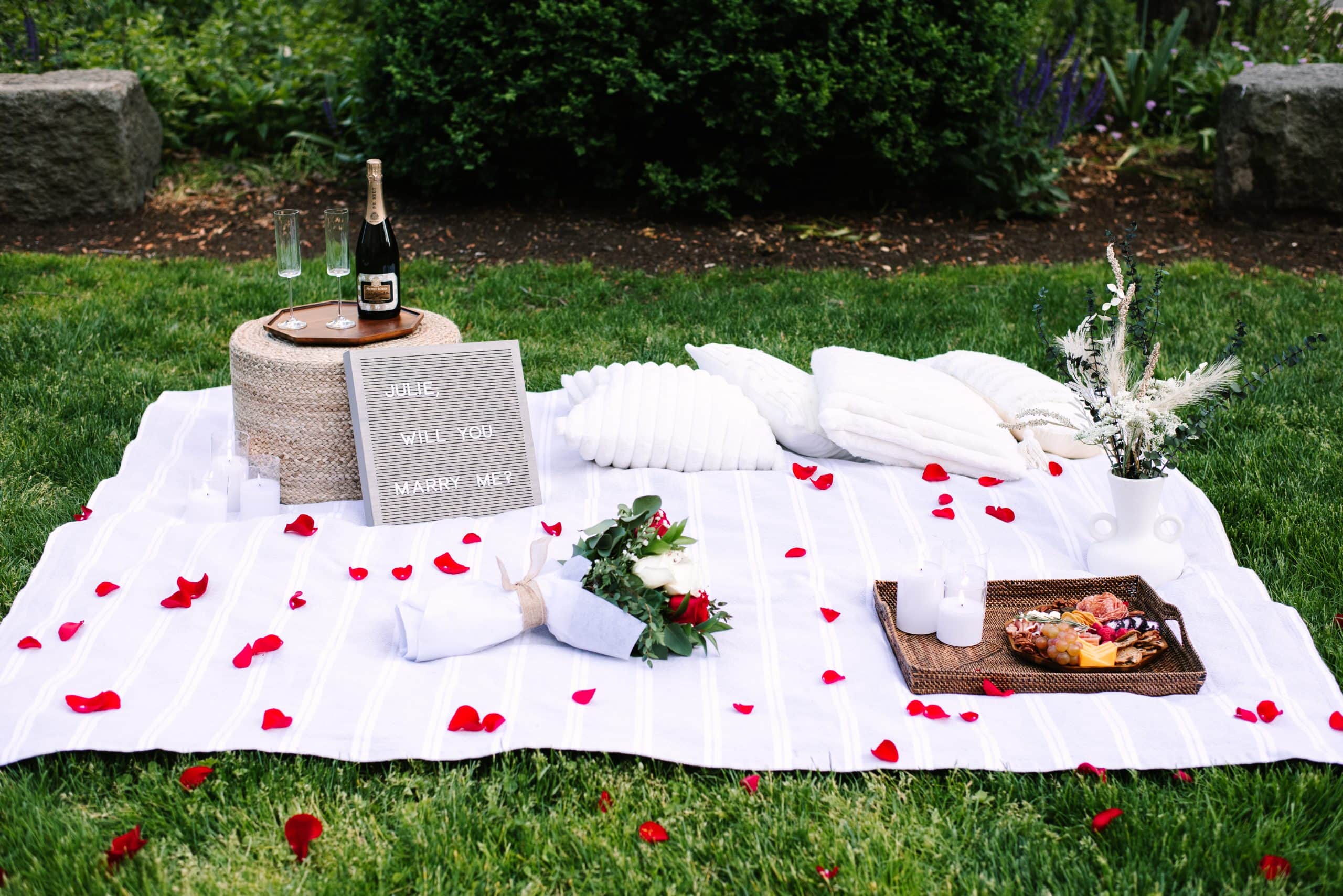 south station white picnic blanket proposal setup with roses, champagne, and a bouquet captured by Boston proposal photographer Meghan Lynch