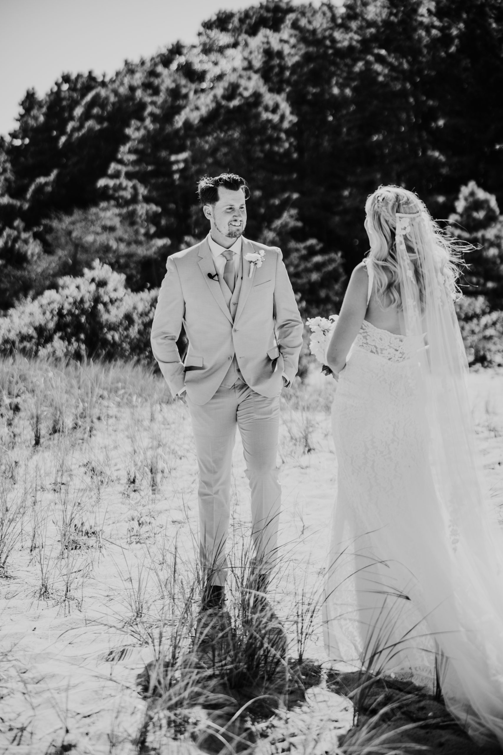 black and white photo of the groom smiling at bride during a first look on the beach during his Popponesset Inn wedding