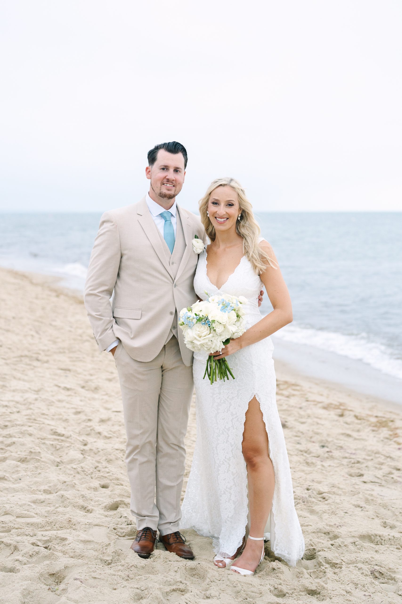 full body portrait of bride and groom on the beach at their Popponesset Inn wedding in Mashpee, MA captured by Meghan Lynch