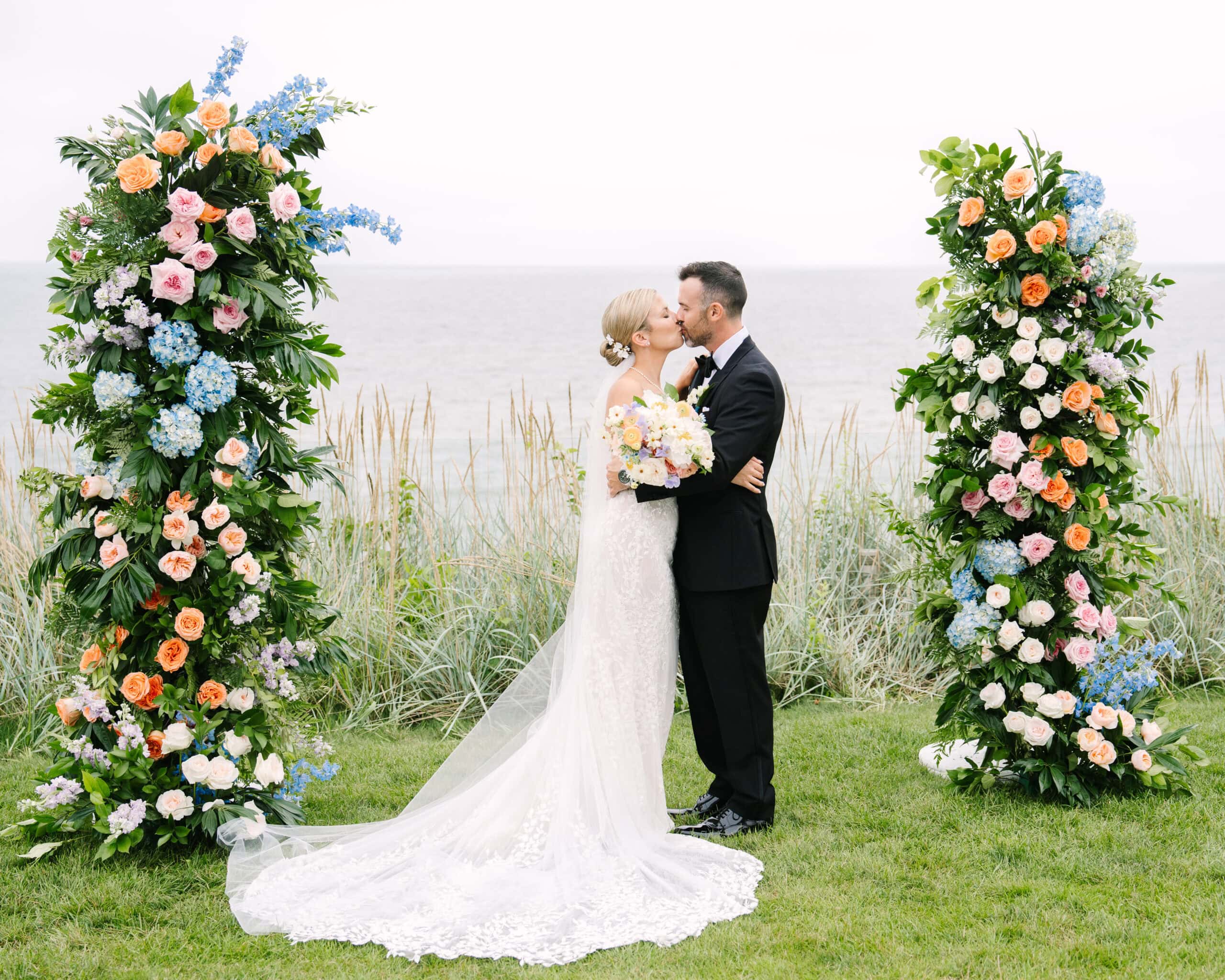 couple kissing in front of floral arch at their pelham house resort wedding