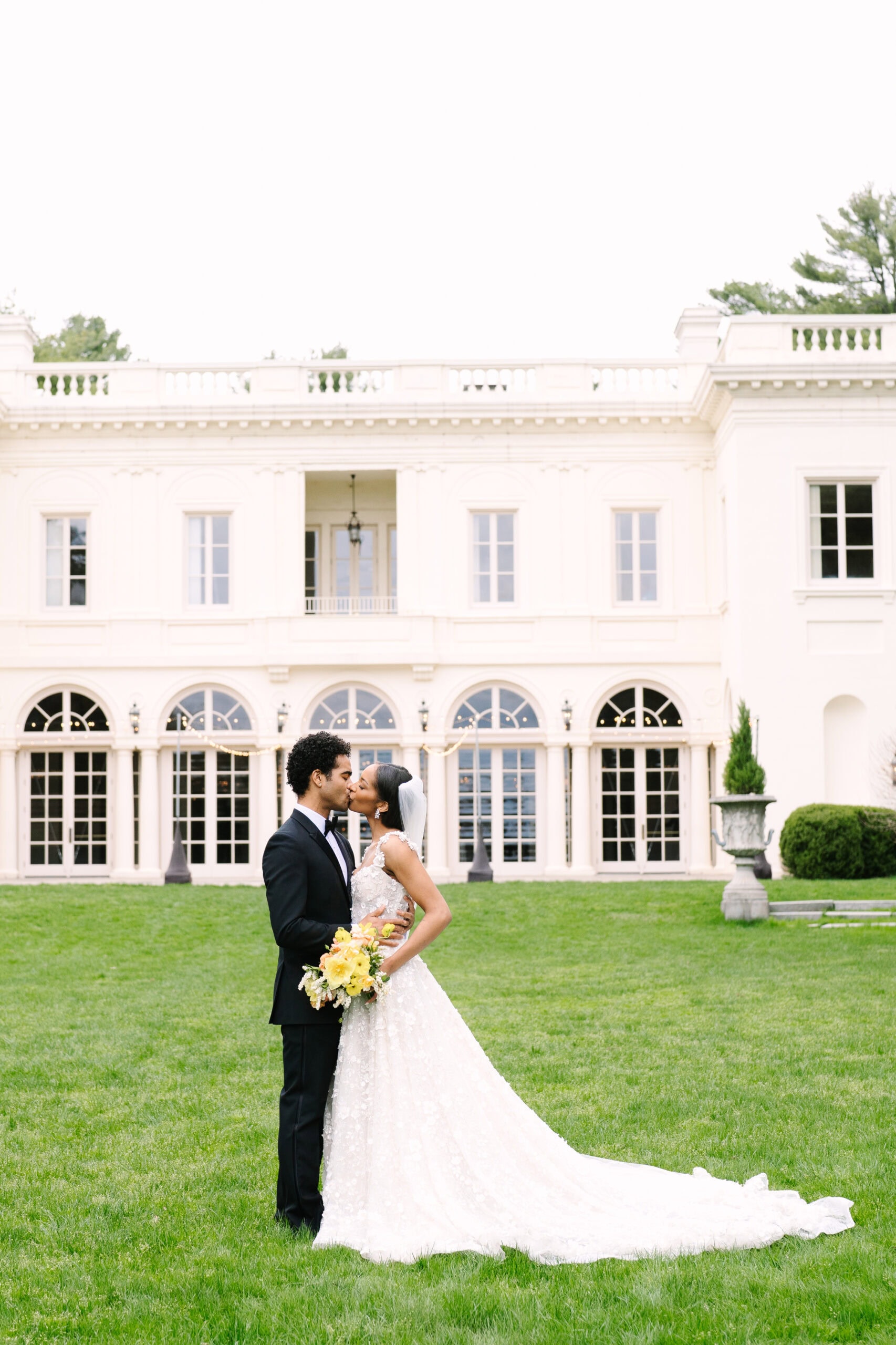 full body shot of the bride and groom kissing in front of the wadsworth mansion in ct