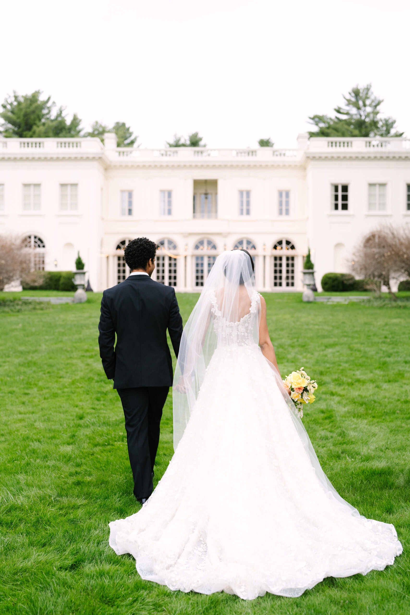 photo of the bride and groom holding hands walking towards the wadsworth mansion during their connecticut wedding