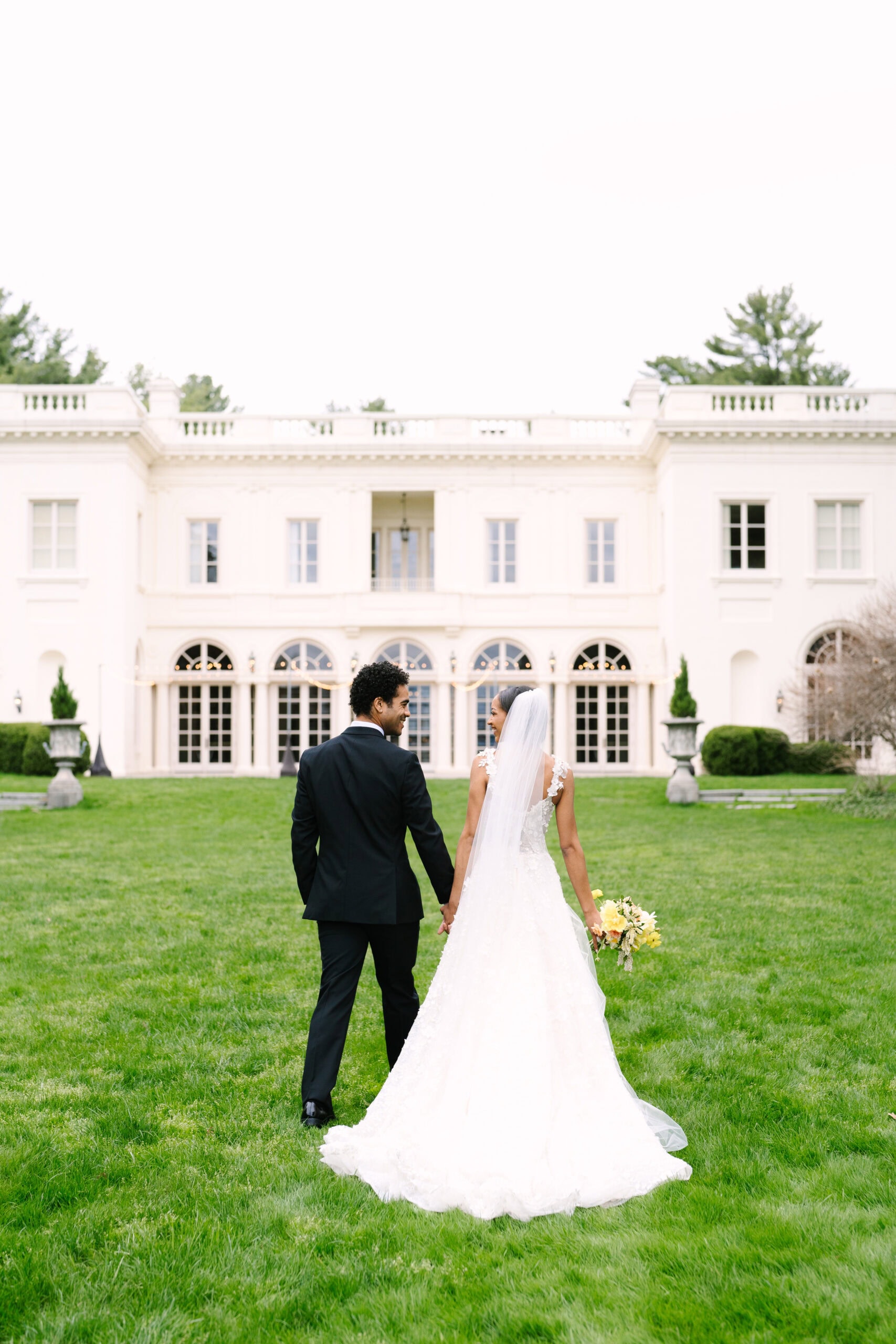 photo of the bride and groom holding hands walking towards the wadsworth mansion during their connecticut wedding