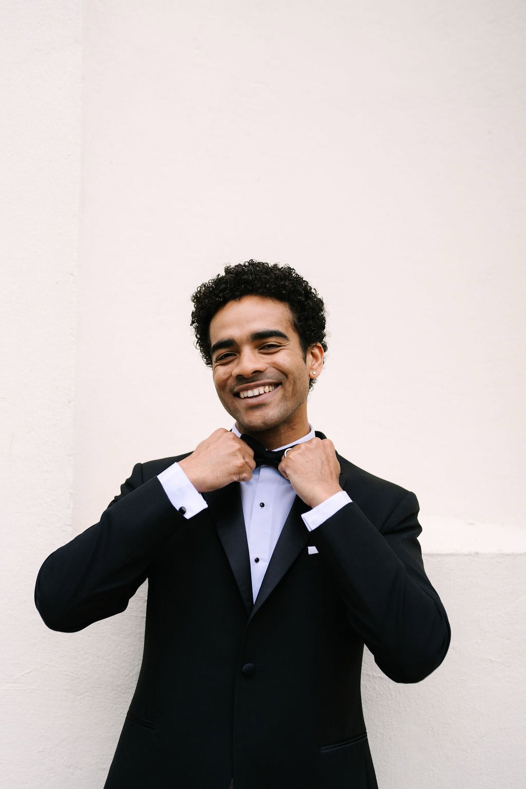 groom portrait smiling and holding the ends of his bowtie at a wadsworth mansion wedding in middletown connecticut