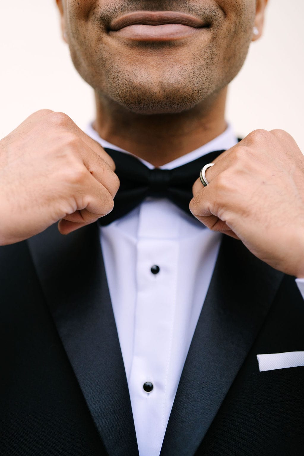 close up on groom's hands holding each end of his bowtie at a wadsworth mansion wedding