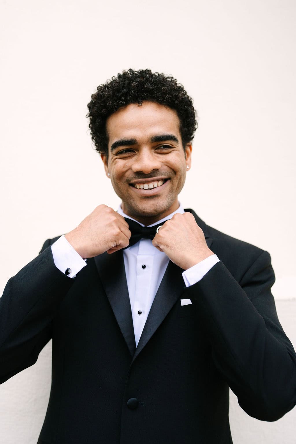 groom portrait smiling and holding the ends of his bowtie at a wadsworth mansion wedding in middletown connecticut