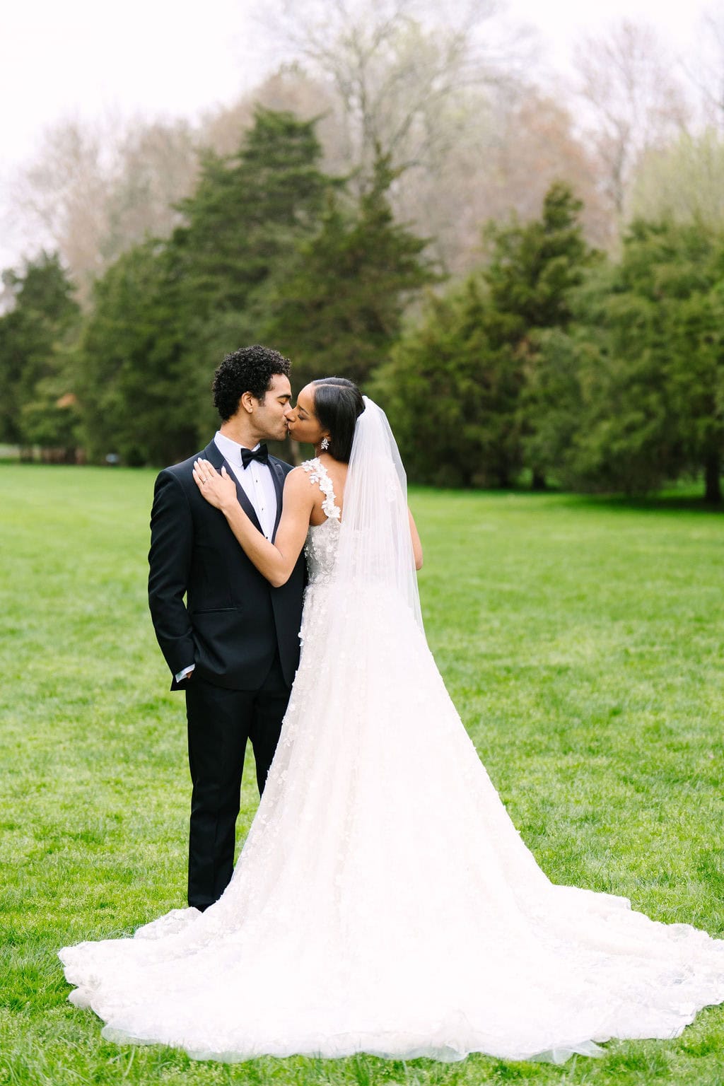 full body portrait of bride and groom kissing amongst the trees during their wadsworth mansion wedding