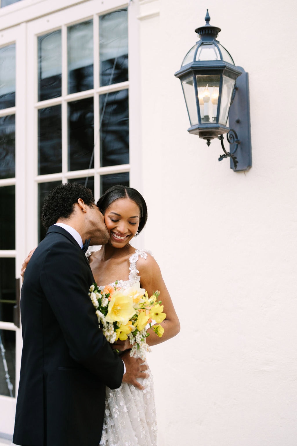 groom kissing bride on the cheek on the patio of the wadsworth mansion 