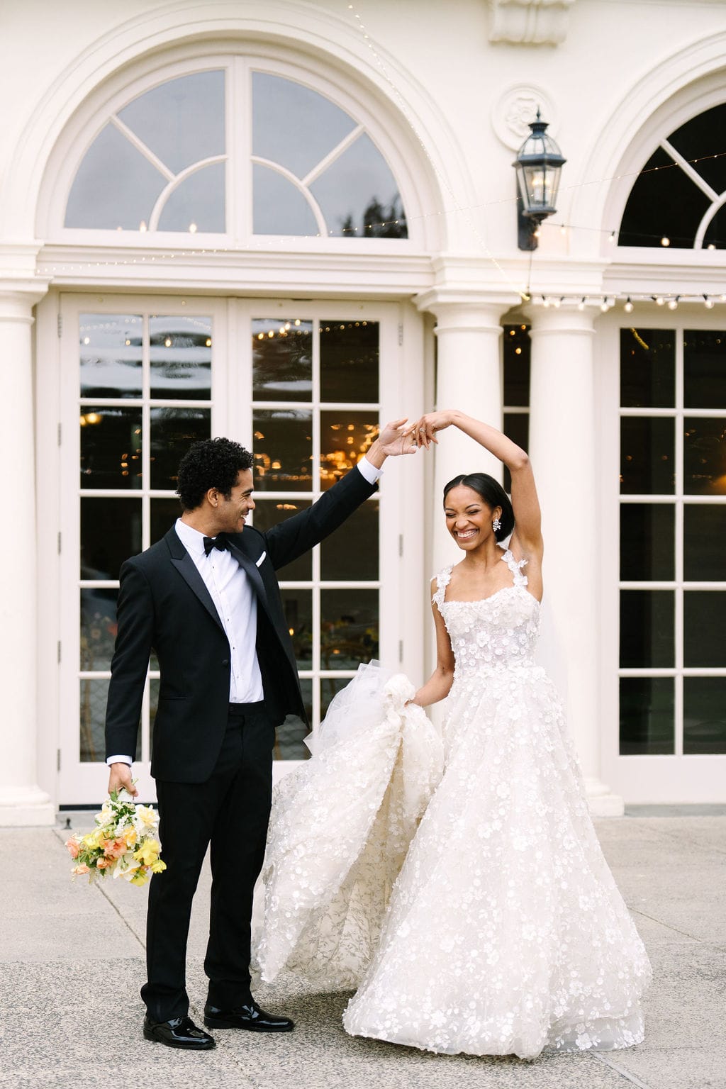 groom holding the bouquet spinning the bride around on the patio of the wadsworth mansion during their ct wedding