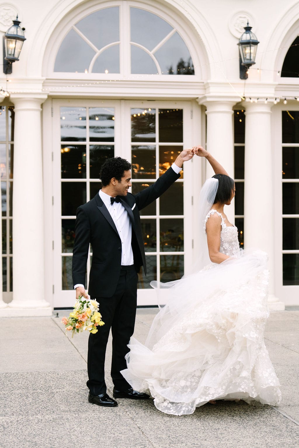 groom holding the bouquet spinning the bride around on the patio of the wadsworth mansion during their ct wedding