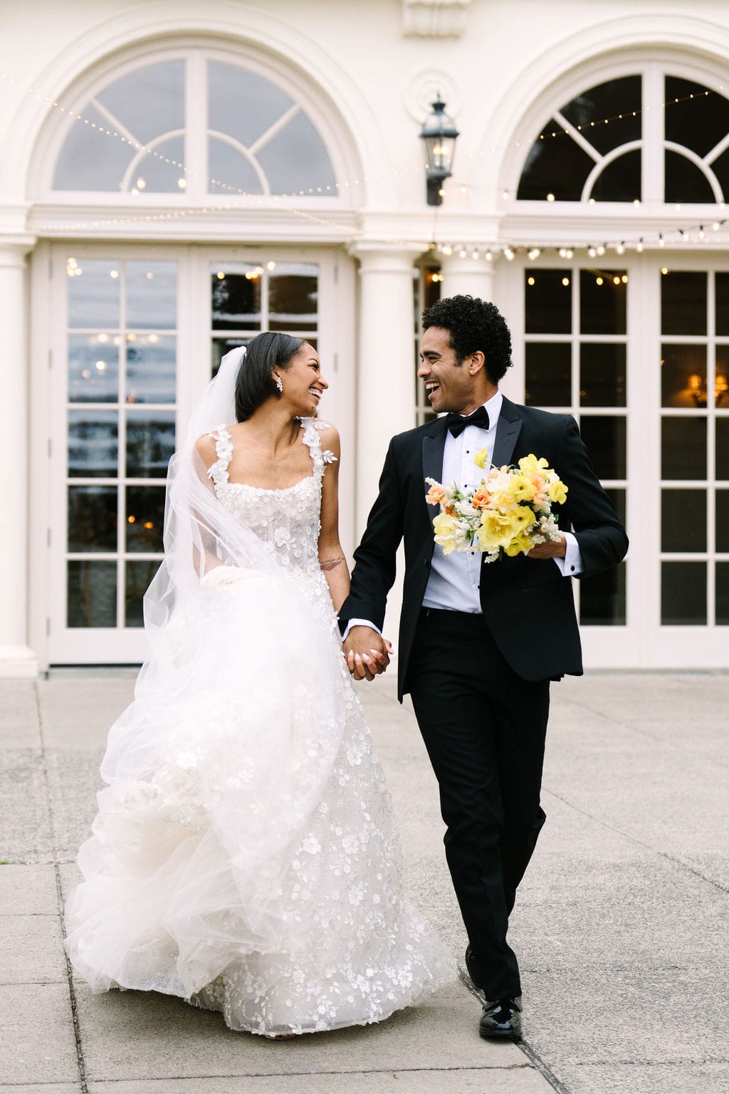 bride and groom holding hands laughing walking on the patio of the wadsworth mansion