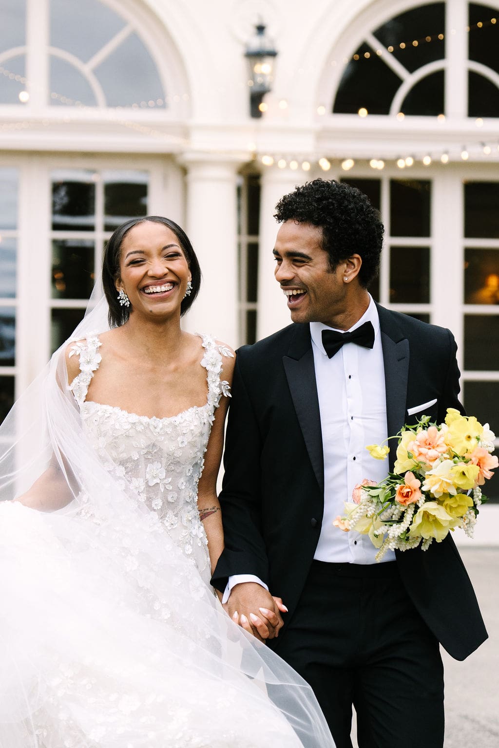 close up of bride and groom holding hands laughing walking on the patio of the wadsworth mansion