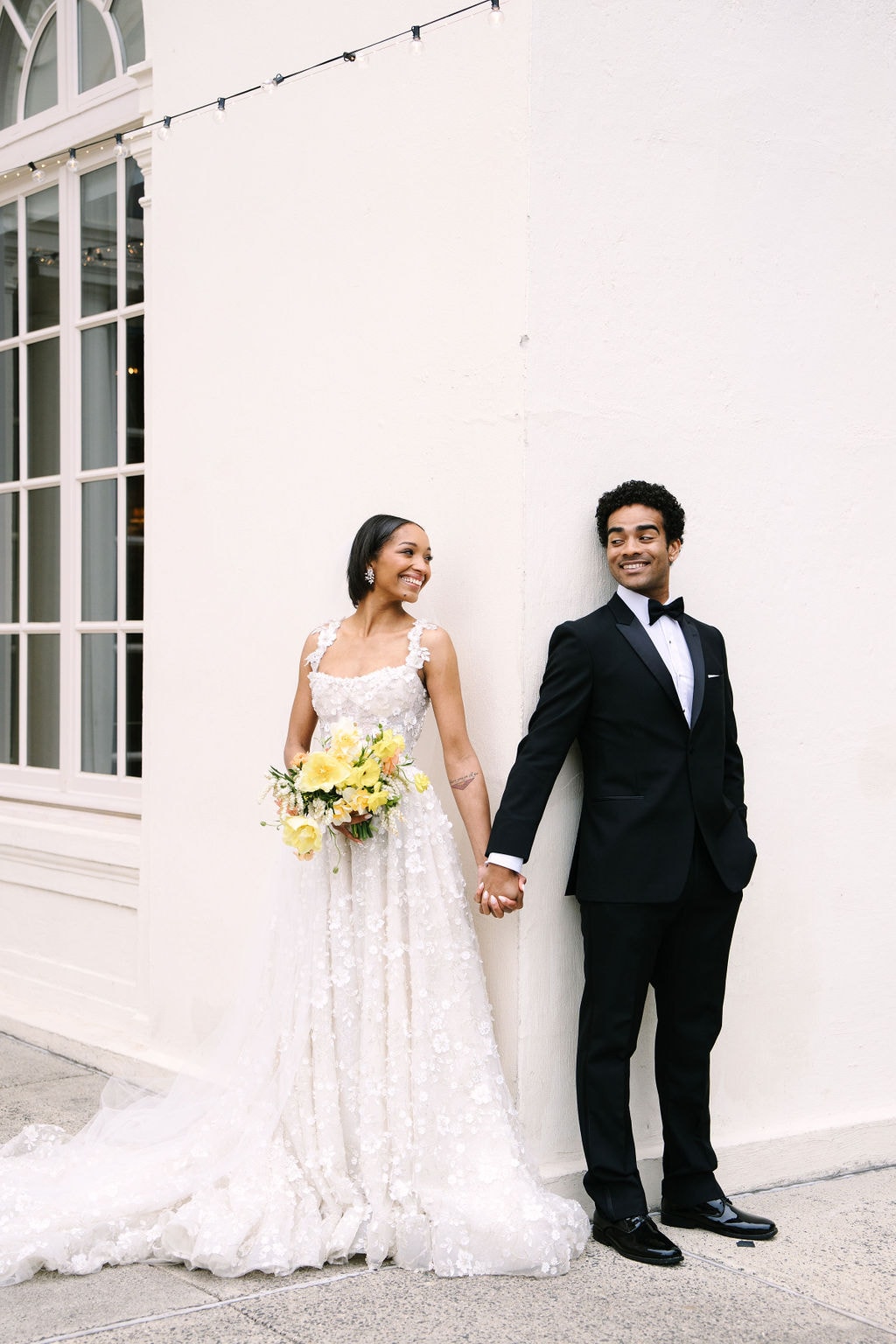 bride and groom holding hands on either side of the wall so they don't see each other before their wadsworth mansion ceremony