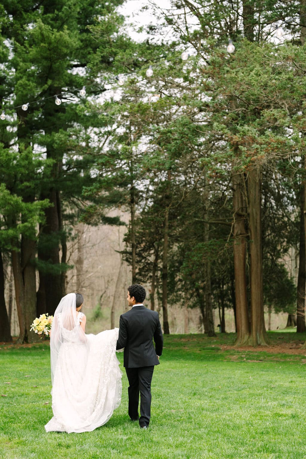 photo of bride and groom walking from behind towards the trees on the wadsworth mansion property