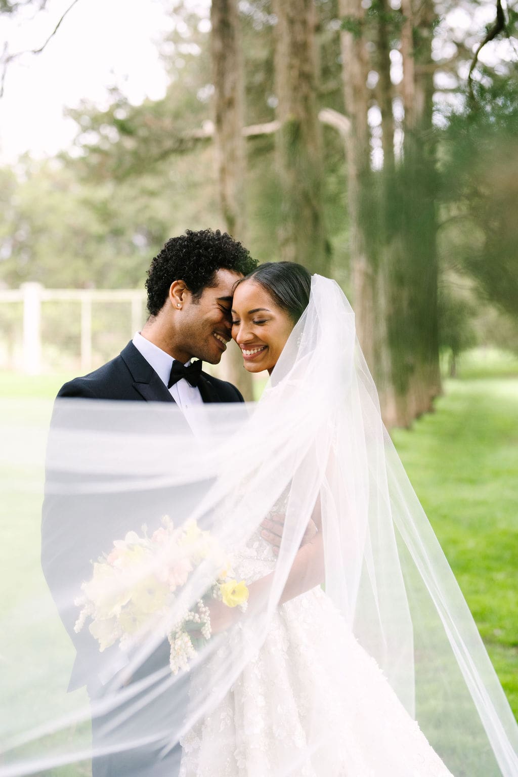 portrait of the bride and groom with the bride's veil blowing in the wind during their wadsworth mansion wedding
