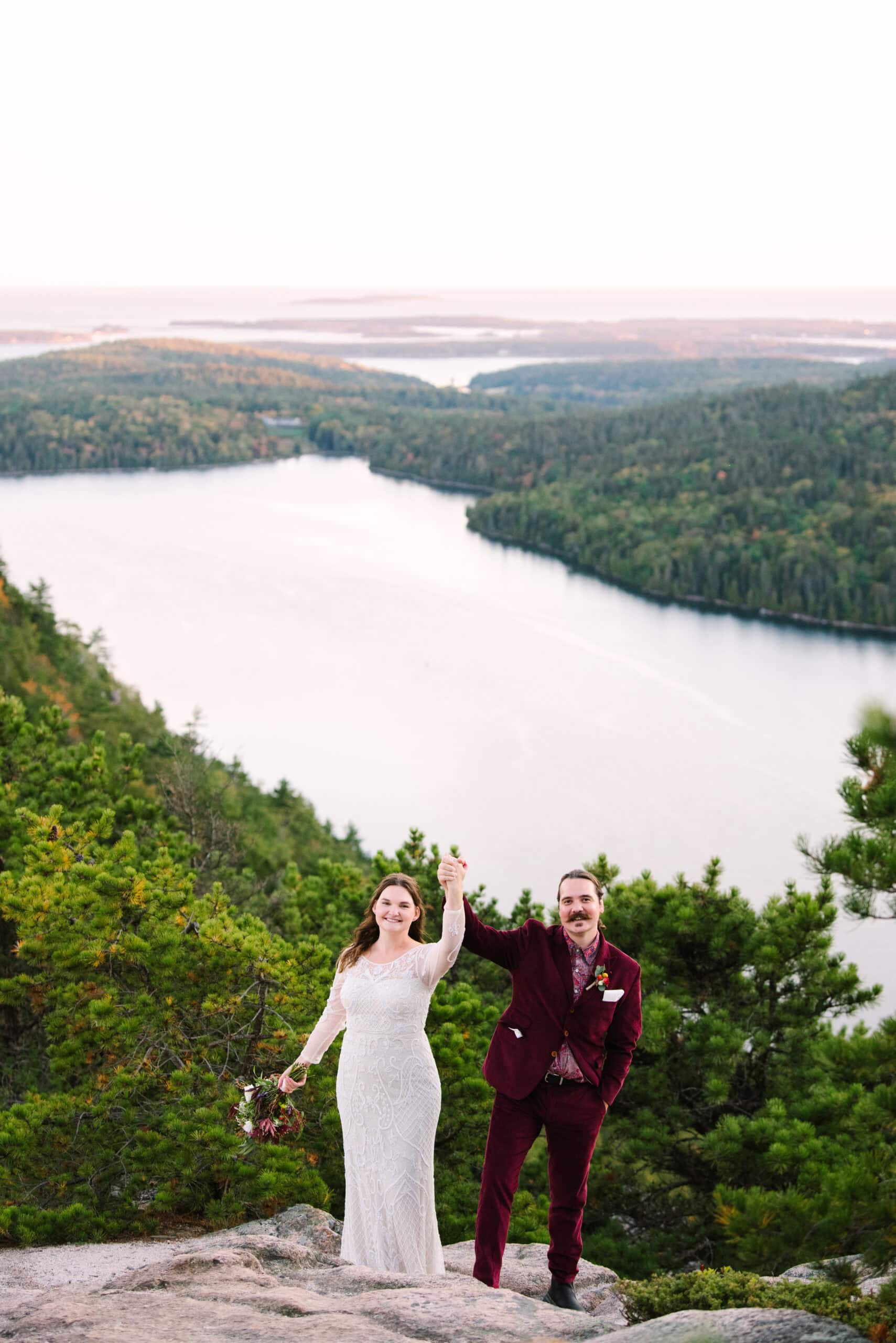 just married couple raising up their arms during their acadia mountain elopement captured by acadia national park elopement photographer meghan lynch