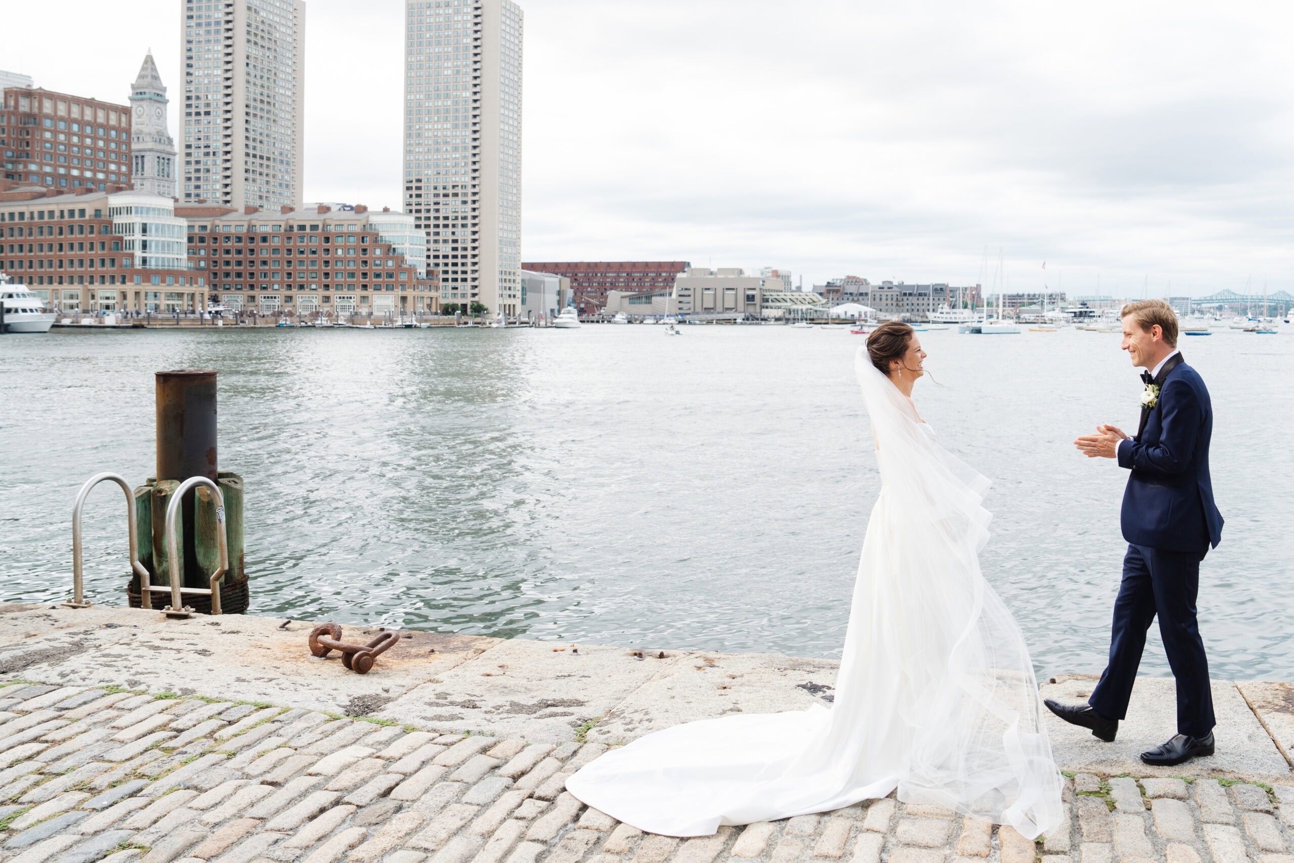 bride and groom first look along the boston harborwalk at fan pier park during their boston ica wedding