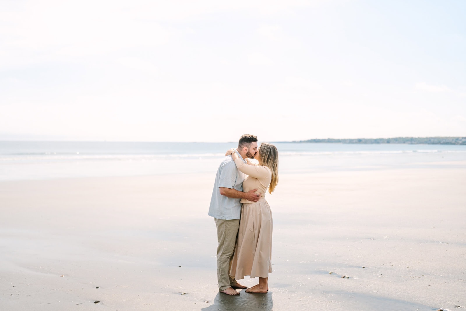engaged couple kissing with the ocean behind them during their nantasket beach engagement session
